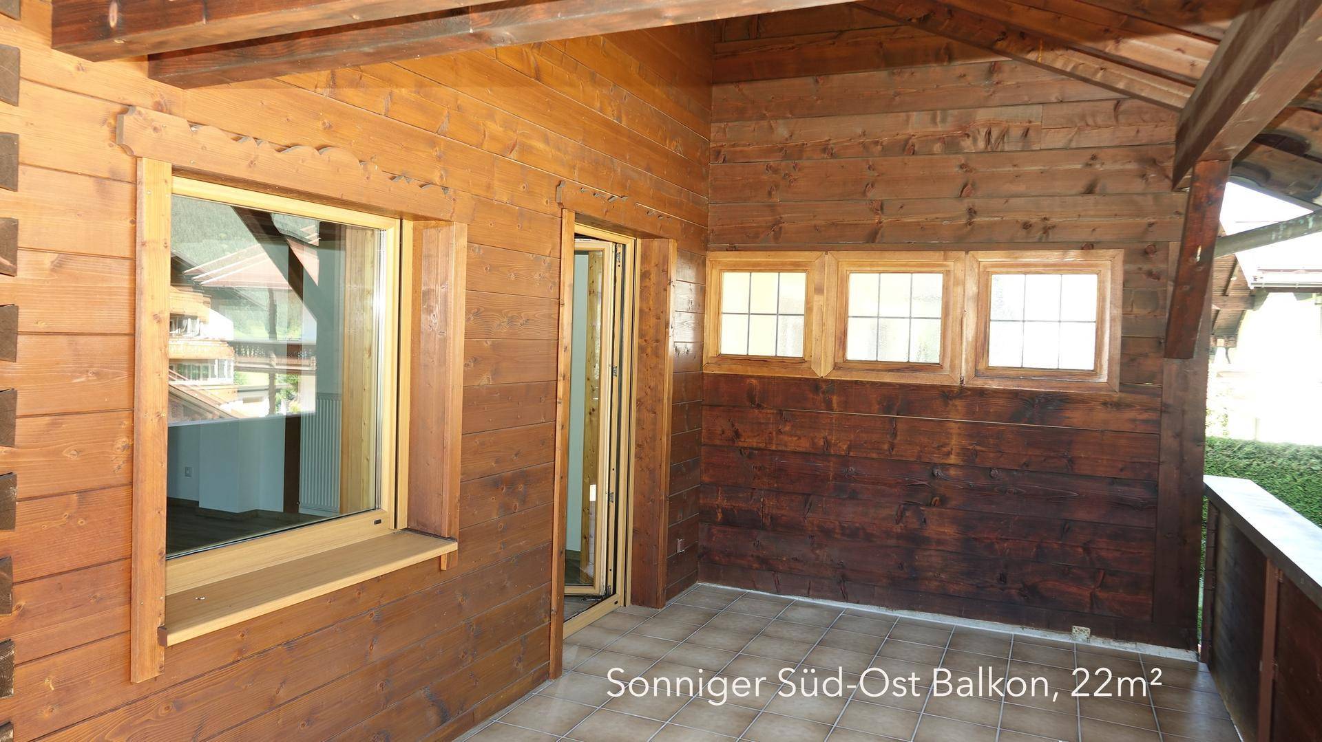 Sonnige Süd-Ost-Balkon mit Fliesenboden und Holzverkleidung, ideal für entspannte Stunden im Freien.