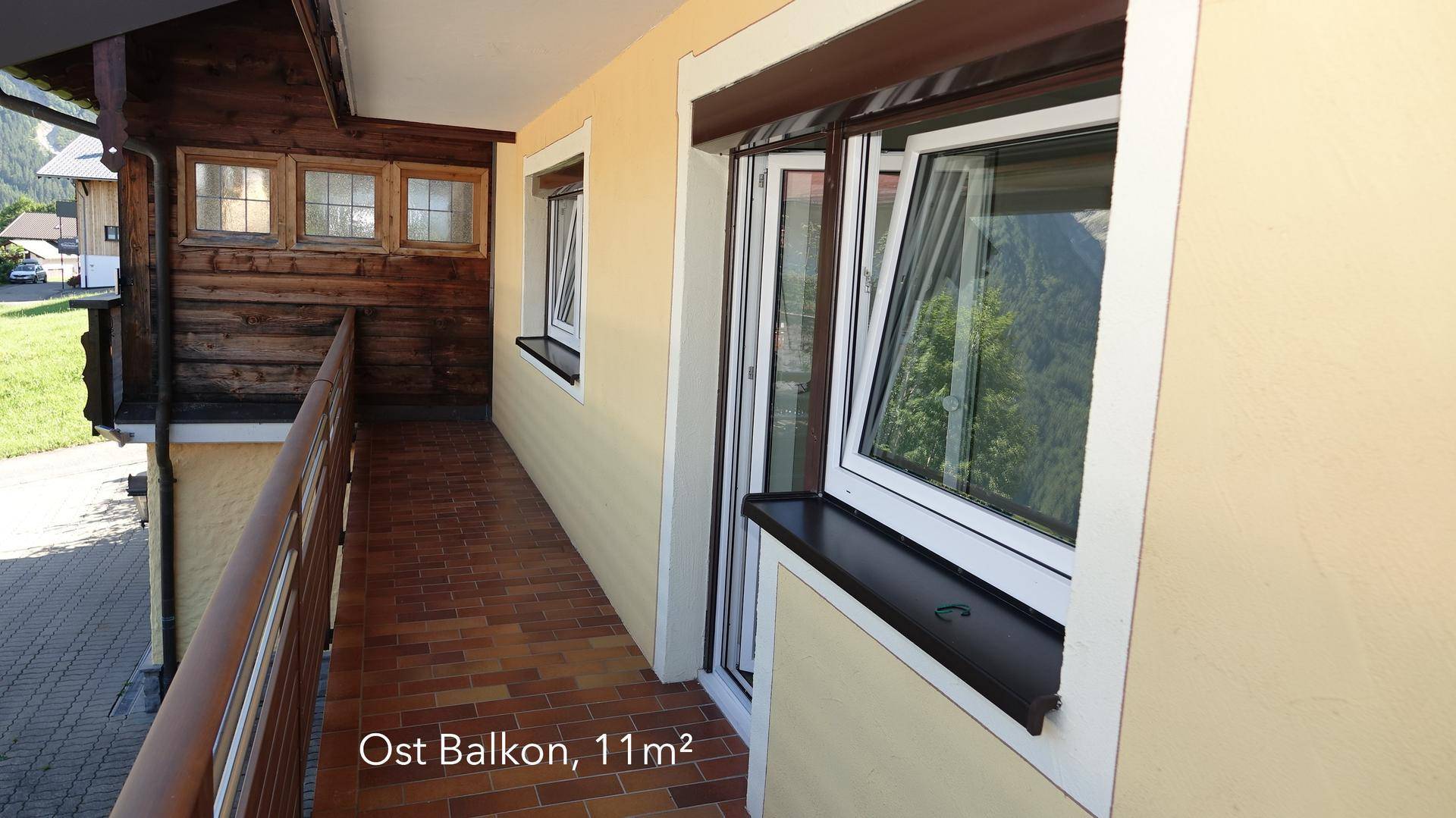 Ostbalkon mit Fliesenboden und Holzverkleidung, ideal für den Morgenkaffee mit Blick auf die Umgebung.