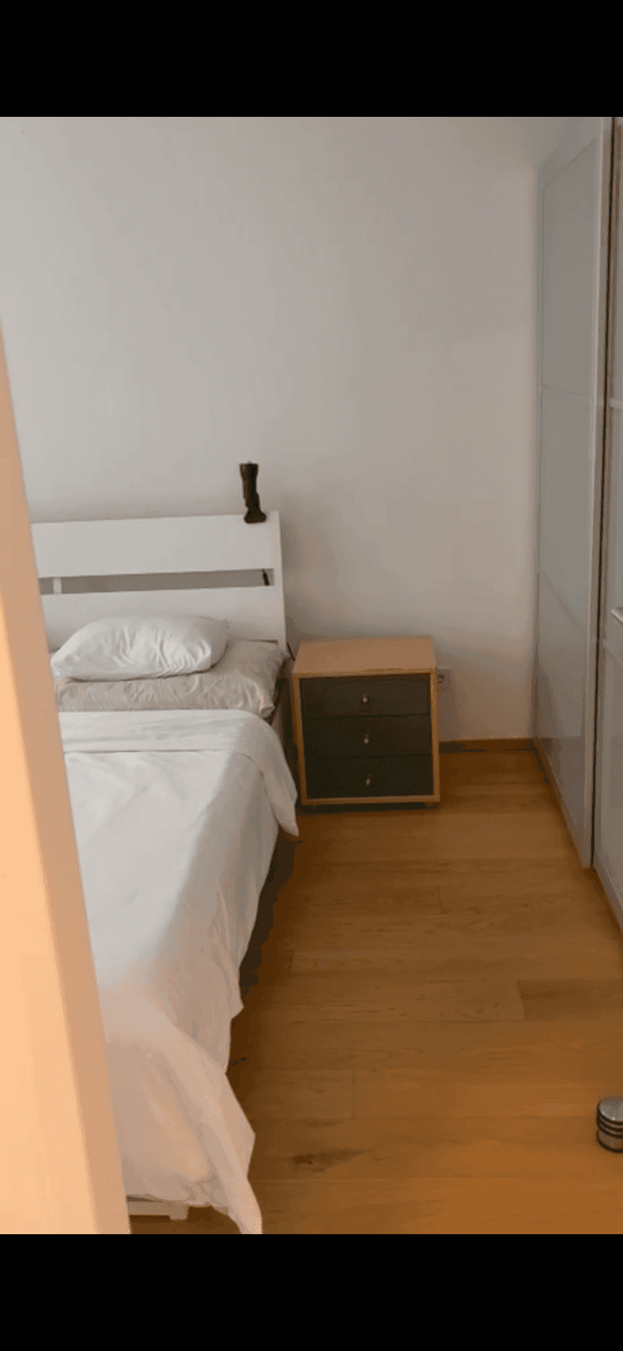 Schlafzimmer mit Bett, Nachttisch und einem großen weißen Kleiderschrank.