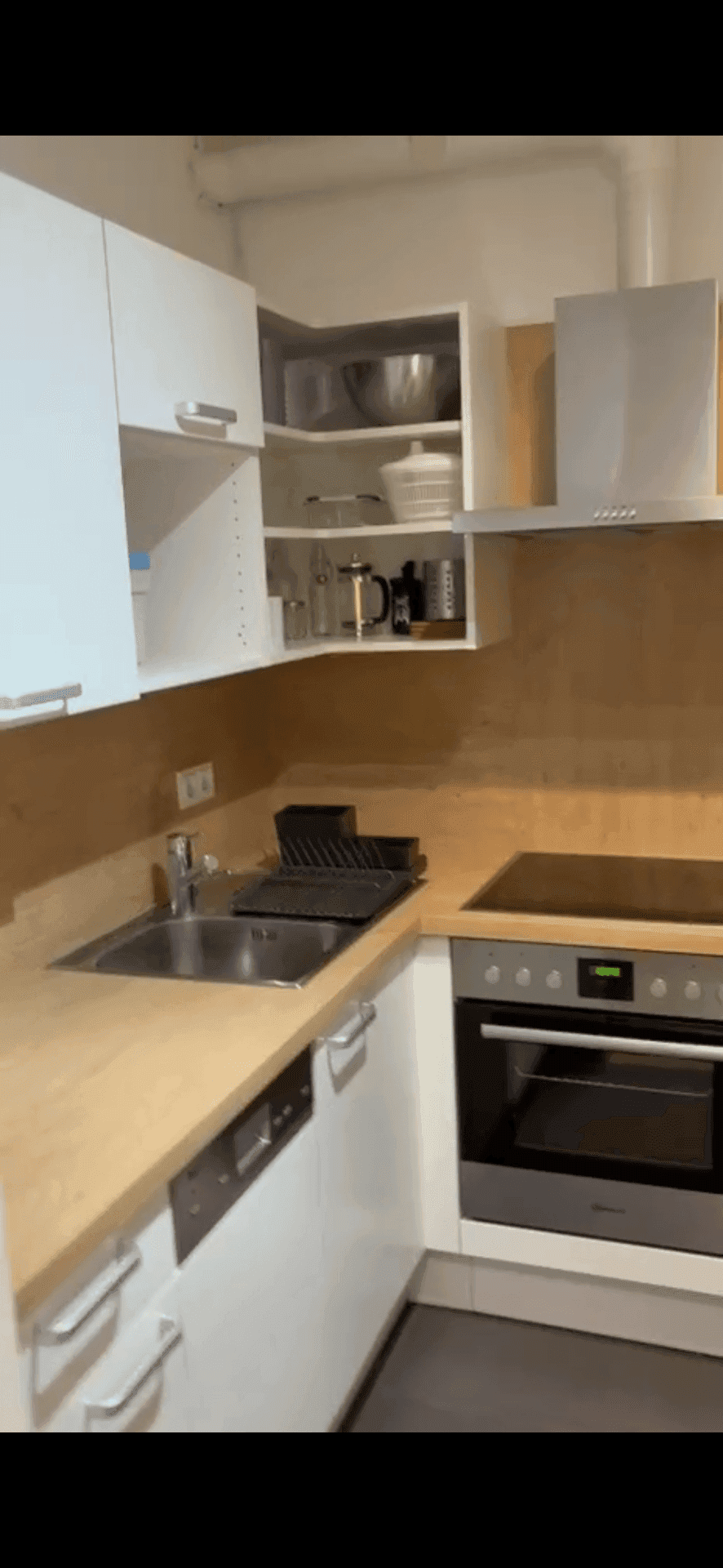 Moderne Küche mit weißen Schränken, Holz-Arbeitsplatte, Spüle und Einbaugeräten.