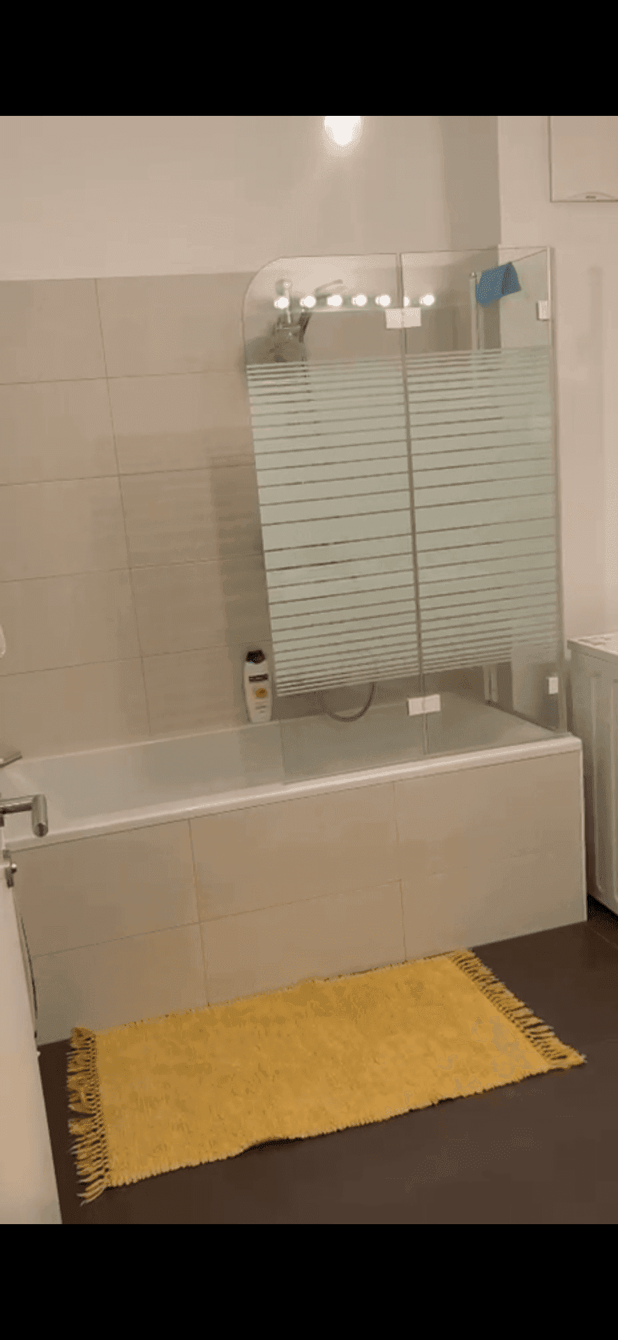 Badezimmer mit Badewanne und moderner Glasabtrennung für den Duschbereich.