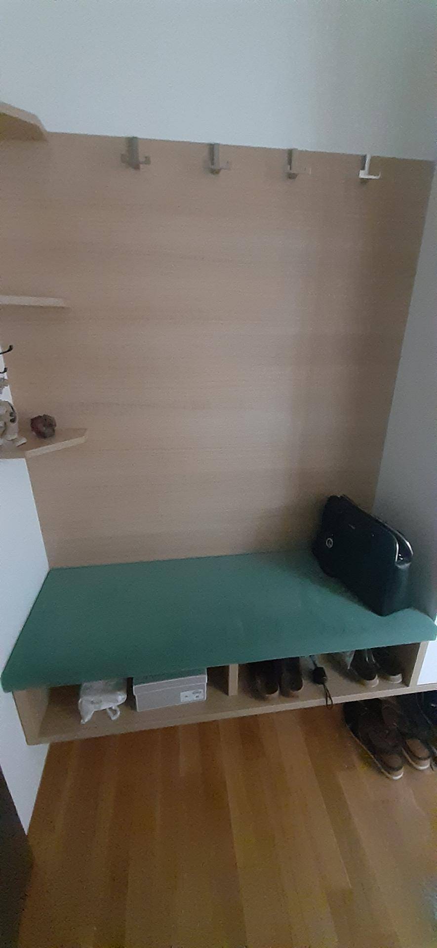 Eingangsbereich mit Garderobenpaneel, Haken und einer Sitzbank mit Stauraum für Schuhe, in Holz und Türkis.