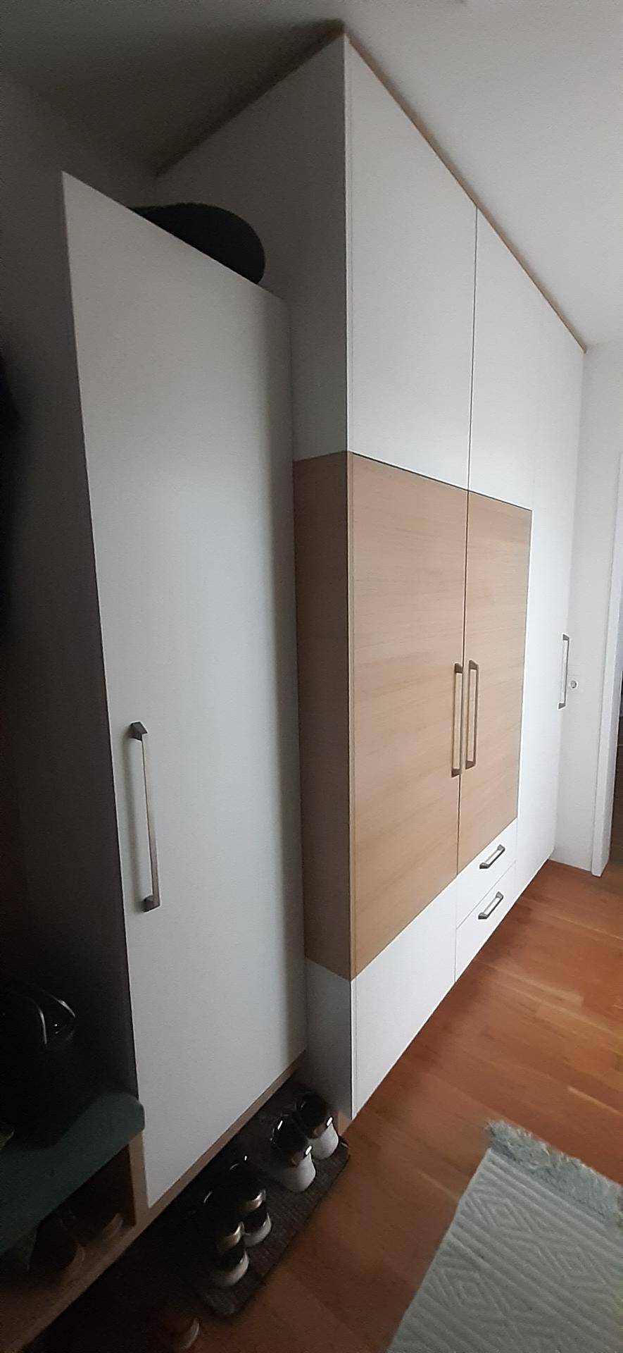Heller Flur mit modernen Einbauschränken in Weiß und Holzoptik sowie einem warmen Holzfußboden.