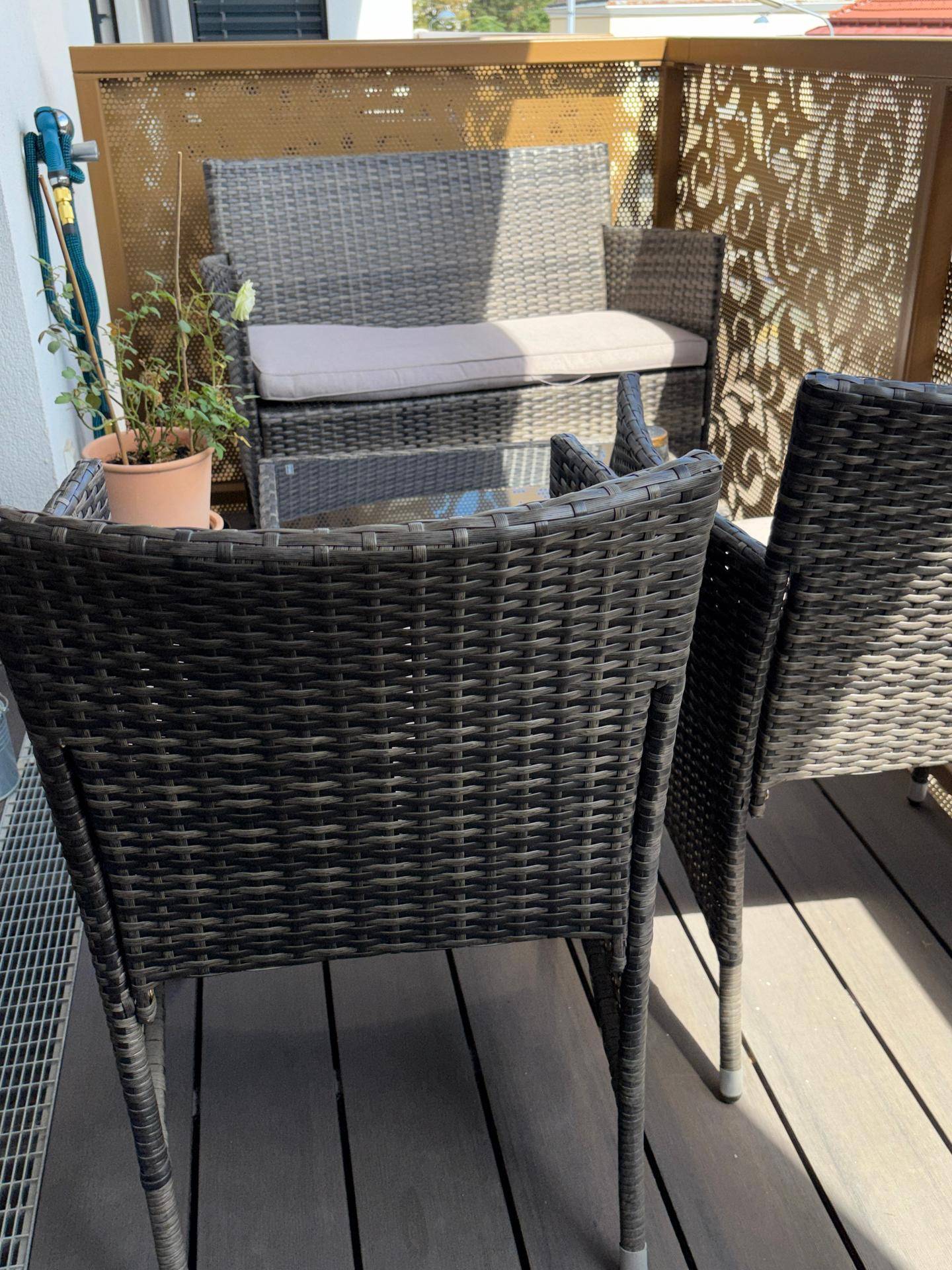 Gemütlicher Balkon mit Rattanmöbeln und dekorativer Sichtschutzwand für entspannte Stunden im Freien.