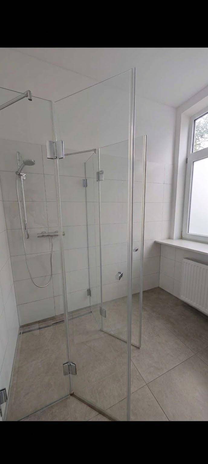 Modernes Badezimmer mit begehbarer Dusche, Fliesenboden und Fenster für Tageslicht.