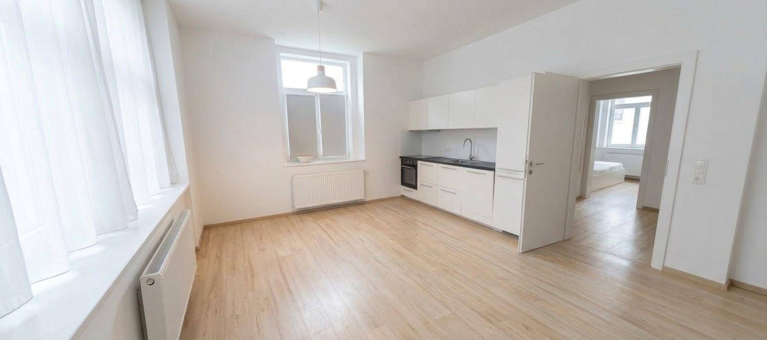 Helle offene Küche mit weißen Schränken, Holzfußboden und großem Fenster.