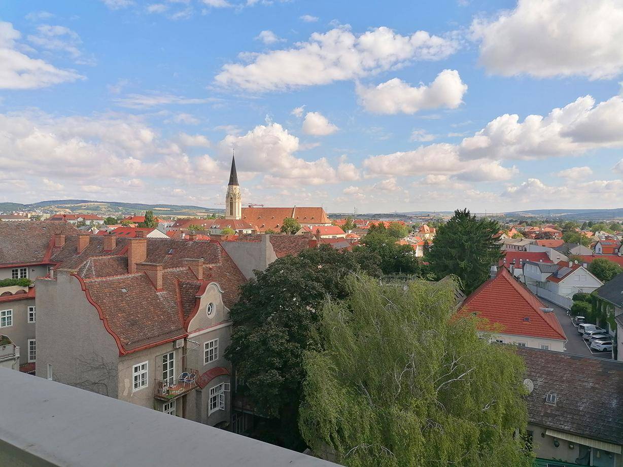 Weitblick vom Balkon über die Stadtlandschaft mit grünen Bäumen und Gebäuden.