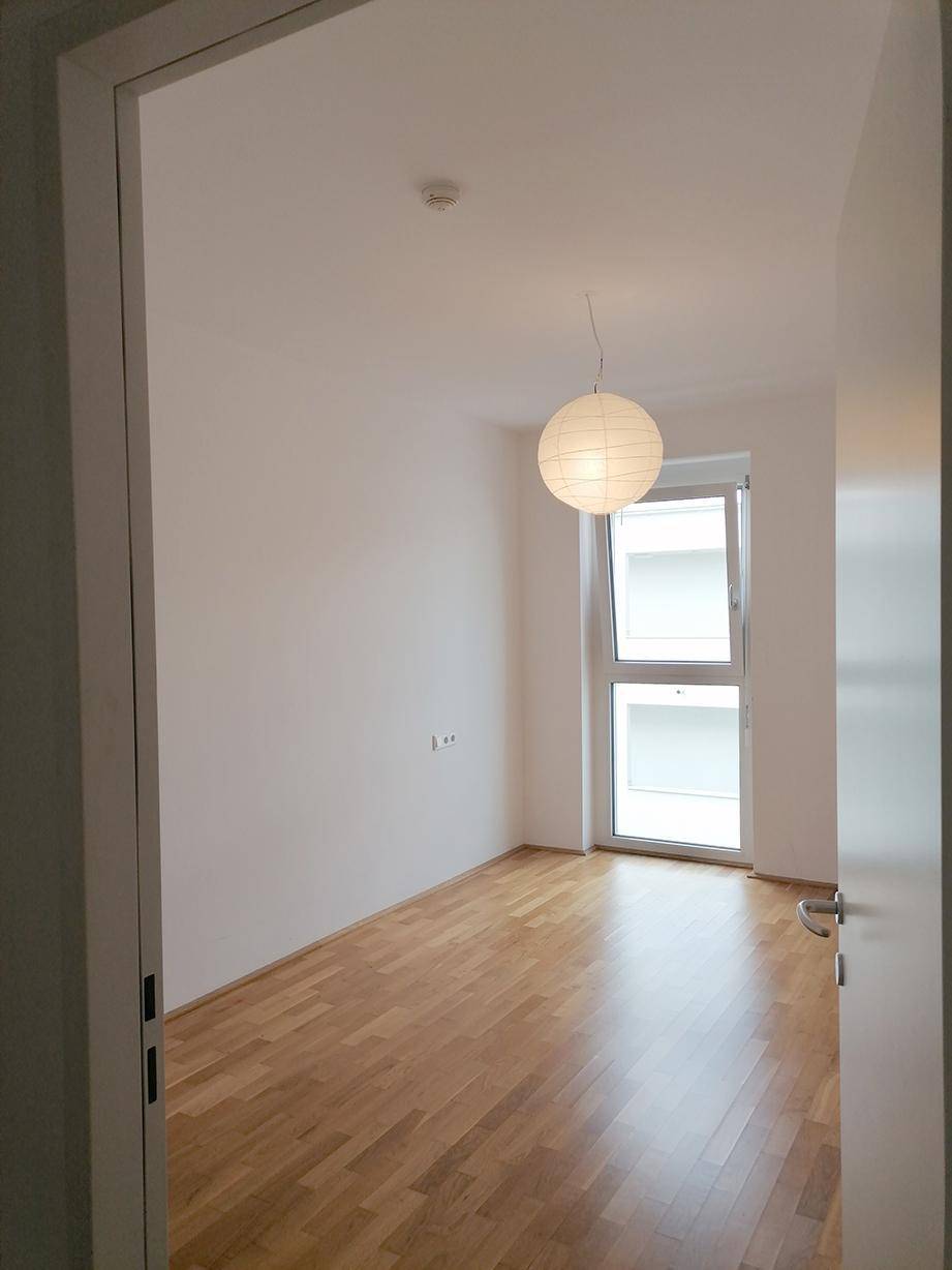 Helles Zimmer mit Parkettboden und Fenster, ideal als Schlaf- oder Arbeitszimmer.