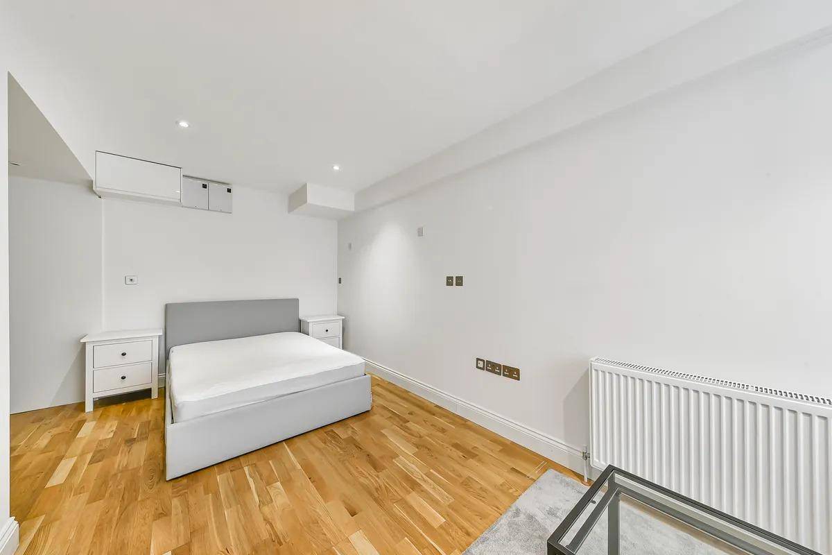Helles Schlafzimmer mit Holzboden, einem Doppelbett und Nachttischen in minimalistischem Stil.
