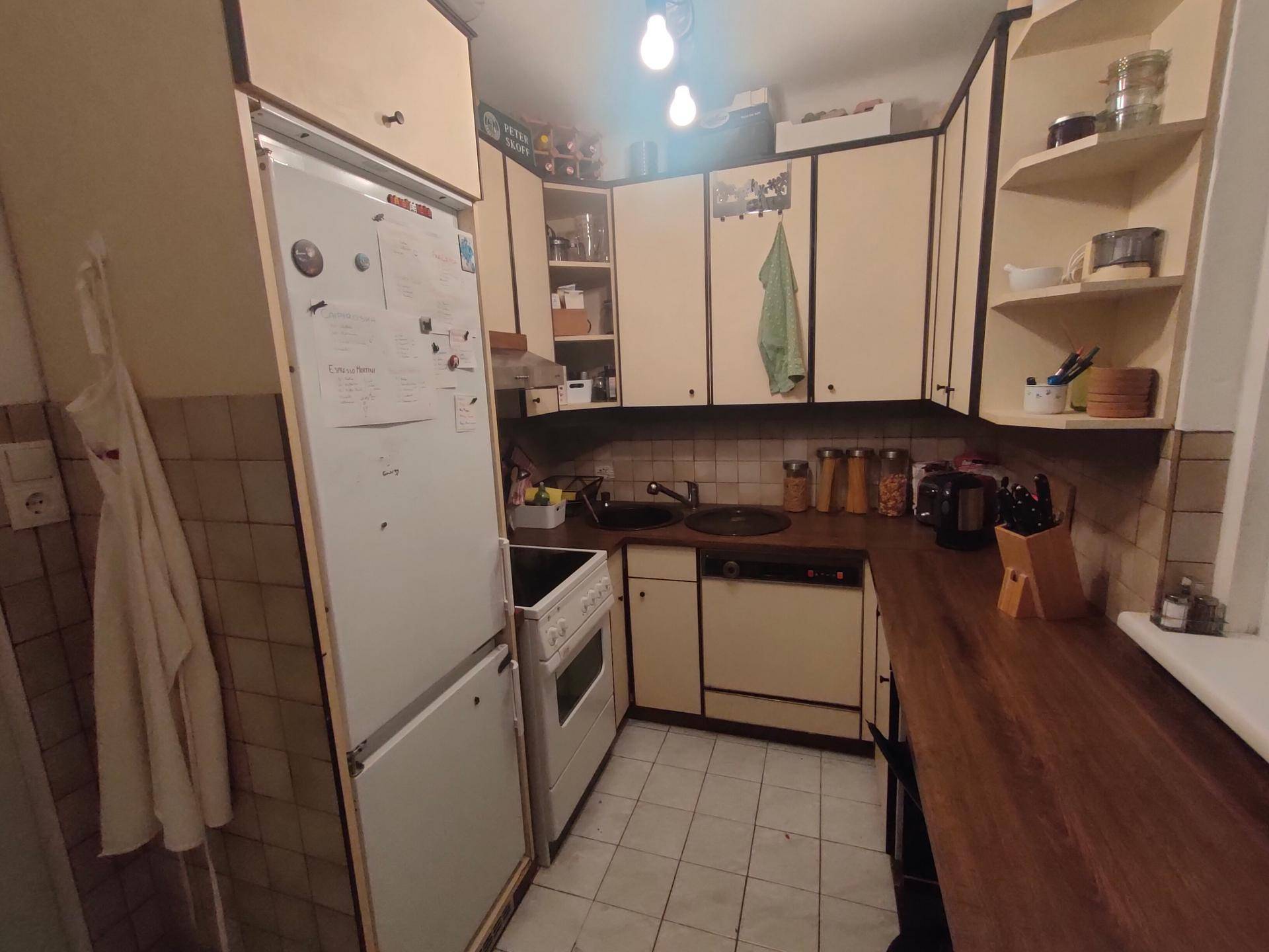 Küche mit Kühlschrank, Herd und hellen Einbauschränken, typisch für ältere Gebäude.
