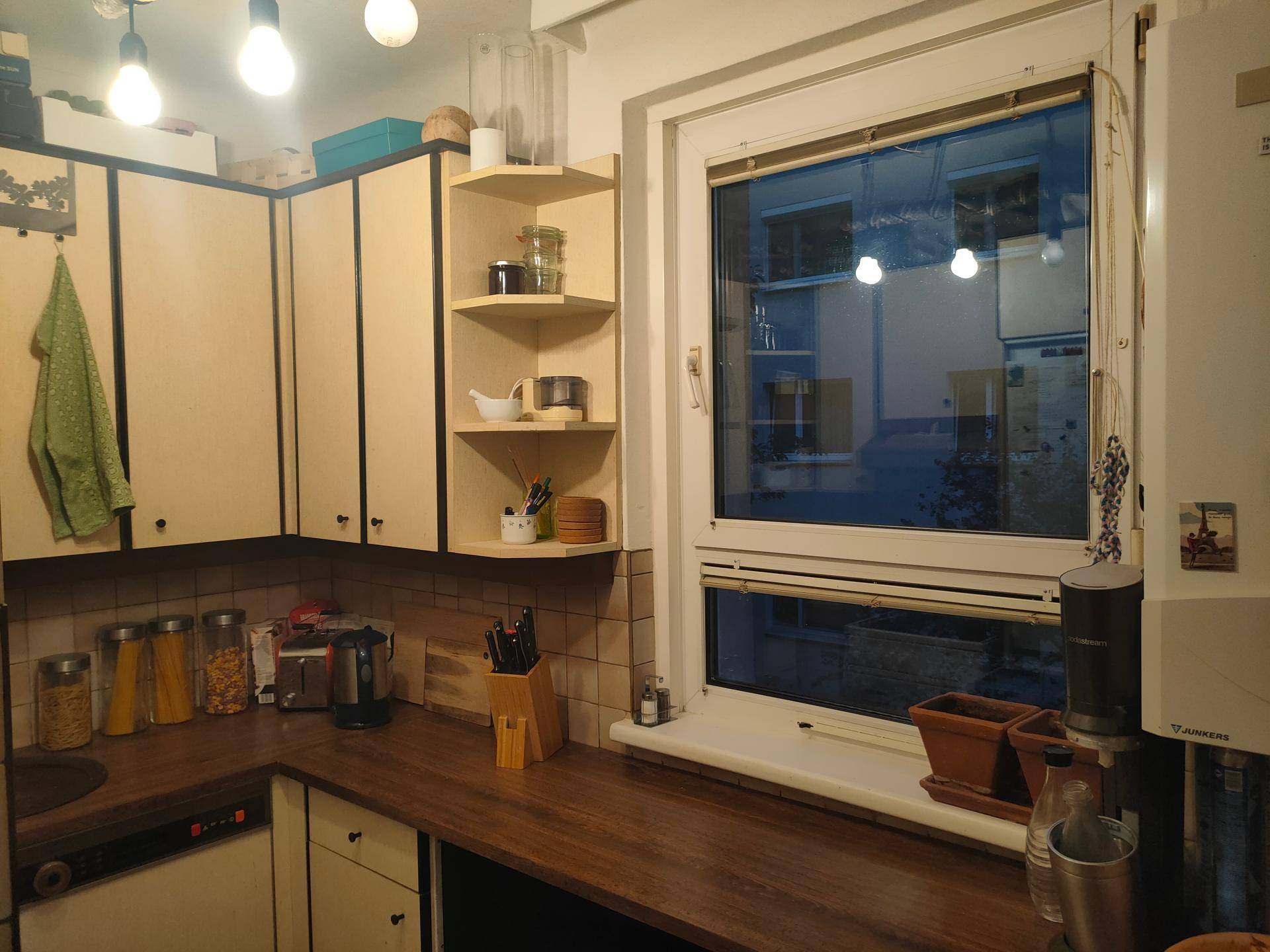 Funktionale Küche mit hellen Schränken, Holz-Arbeitsplatten und einem Fenster.