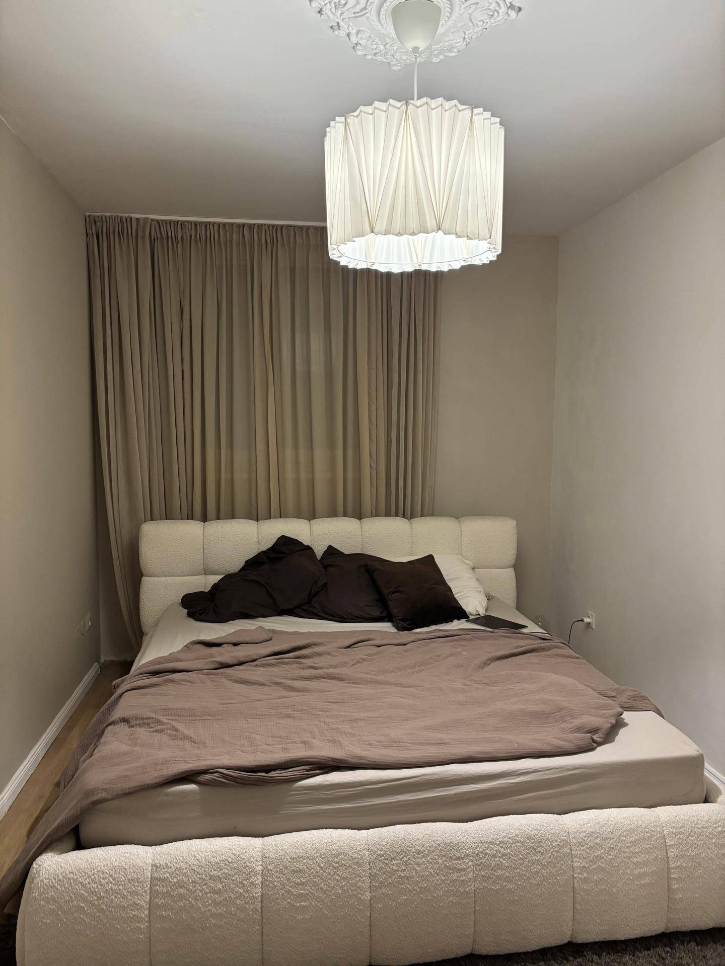 Gemütliches Schlafzimmer mit großem Doppelbett und beigen Vorhängen.