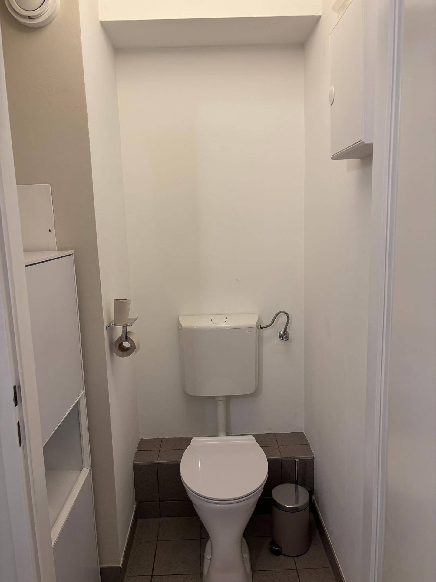 Kleines separates WC mit Toilette und Fliesenboden.