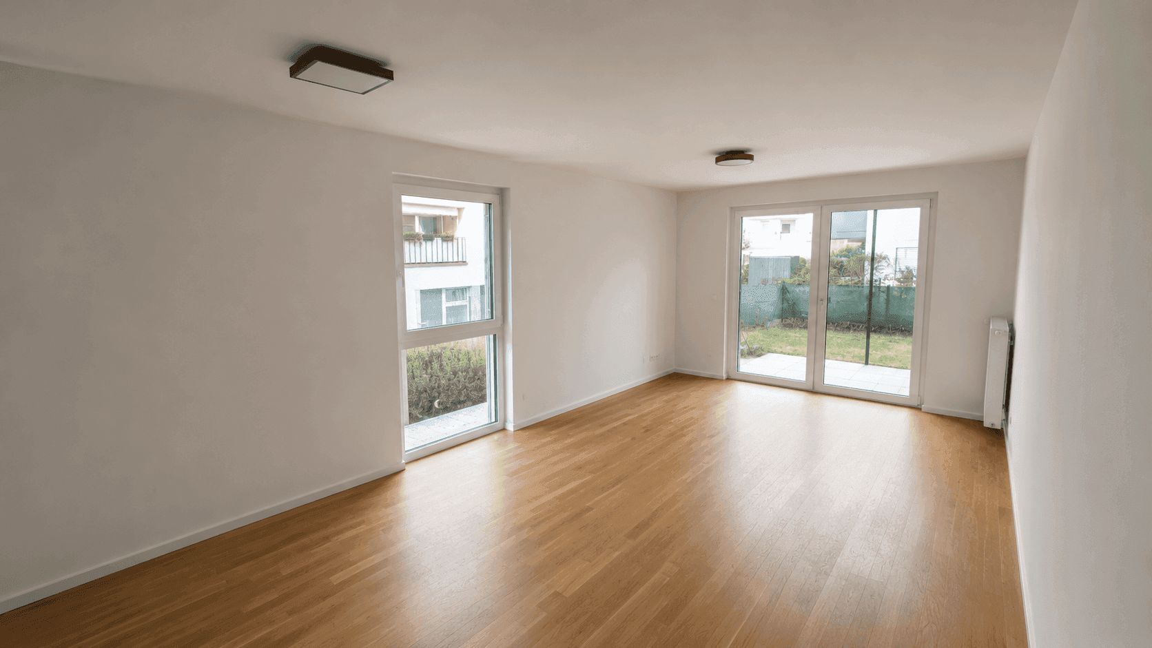 Heller Wohnraum mit Holzboden und großen Schiebetüren zum privaten Gartenbereich.