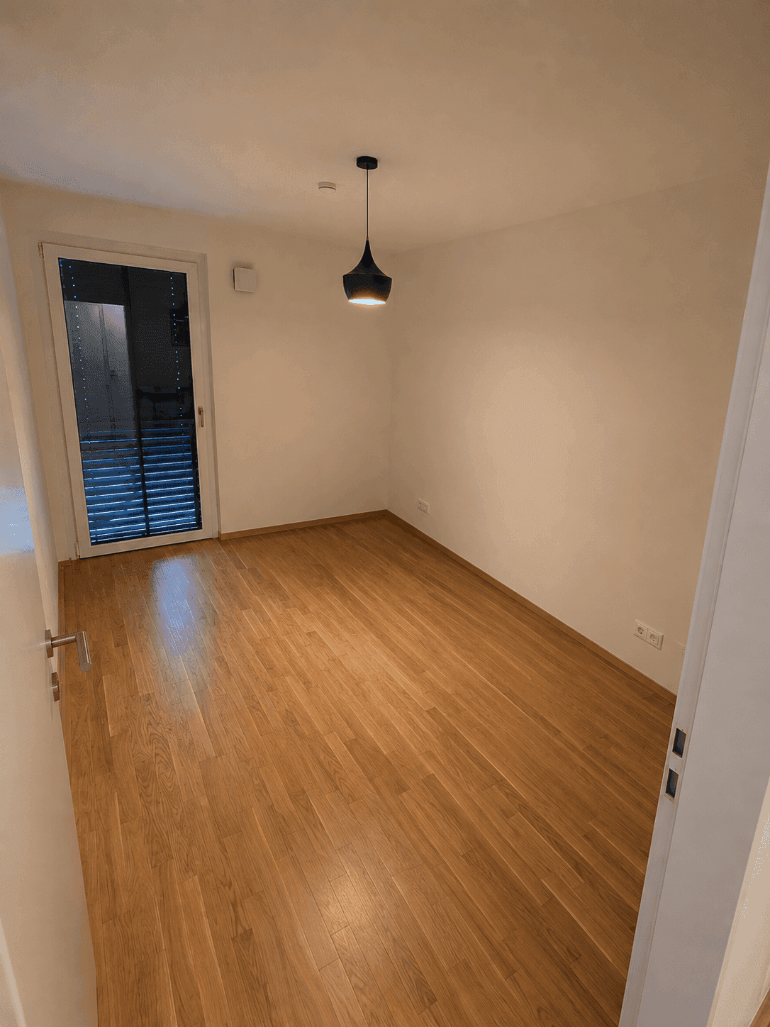 Ruhiges Zimmer mit Holzboden und Tür mit Jalousien für Privatsphäre.