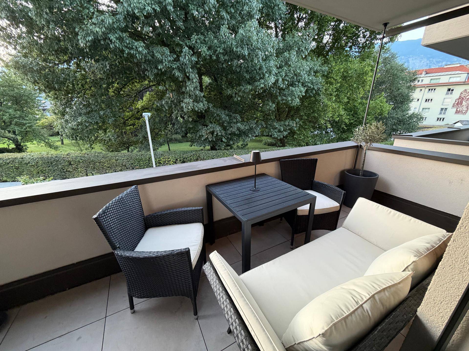 Geräumiger Balkon mit modernen Outdoor-Möbeln und üppiger grüner Umgebung.