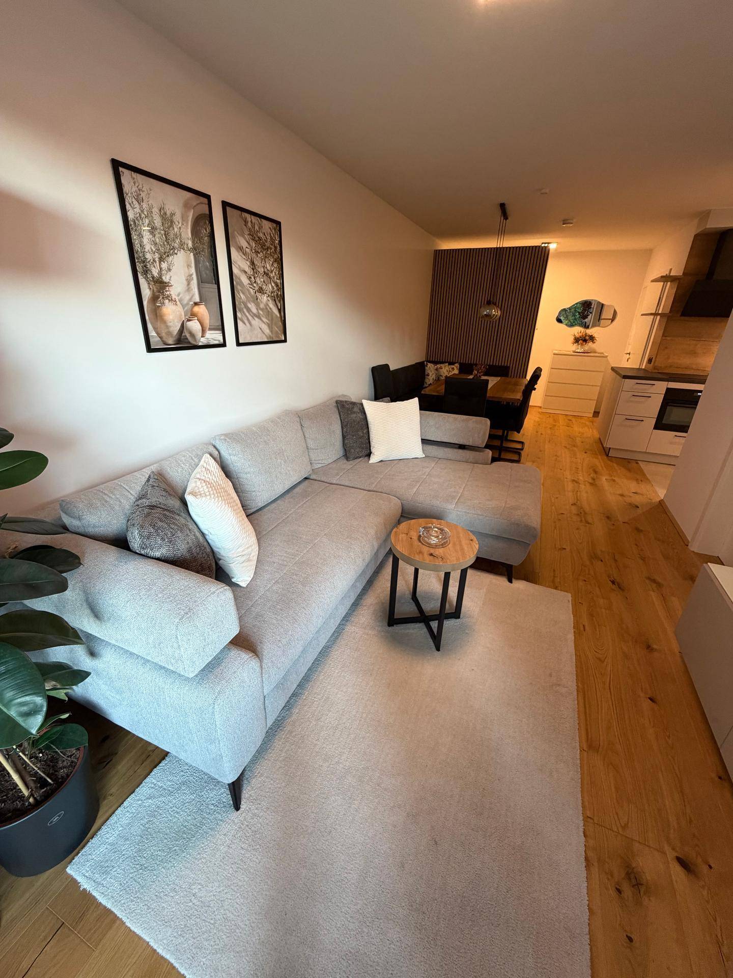 Moderner Wohn- und Essbereich mit Ecksofa, Holzboden und stilvoller Holzwand.