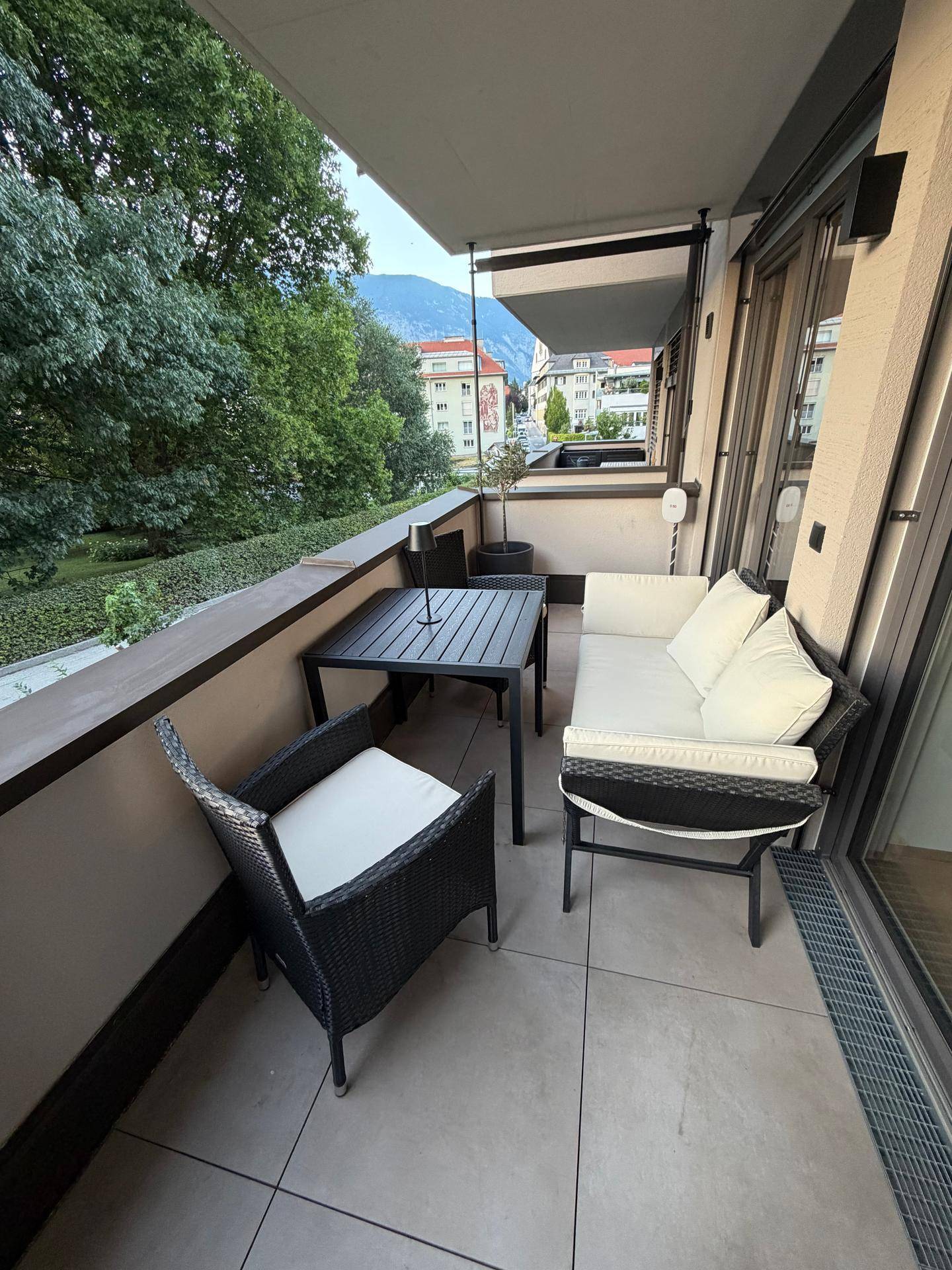 Möblierter Balkon mit Sitzgelegenheiten, Blick ins Grüne und auf die Berge.