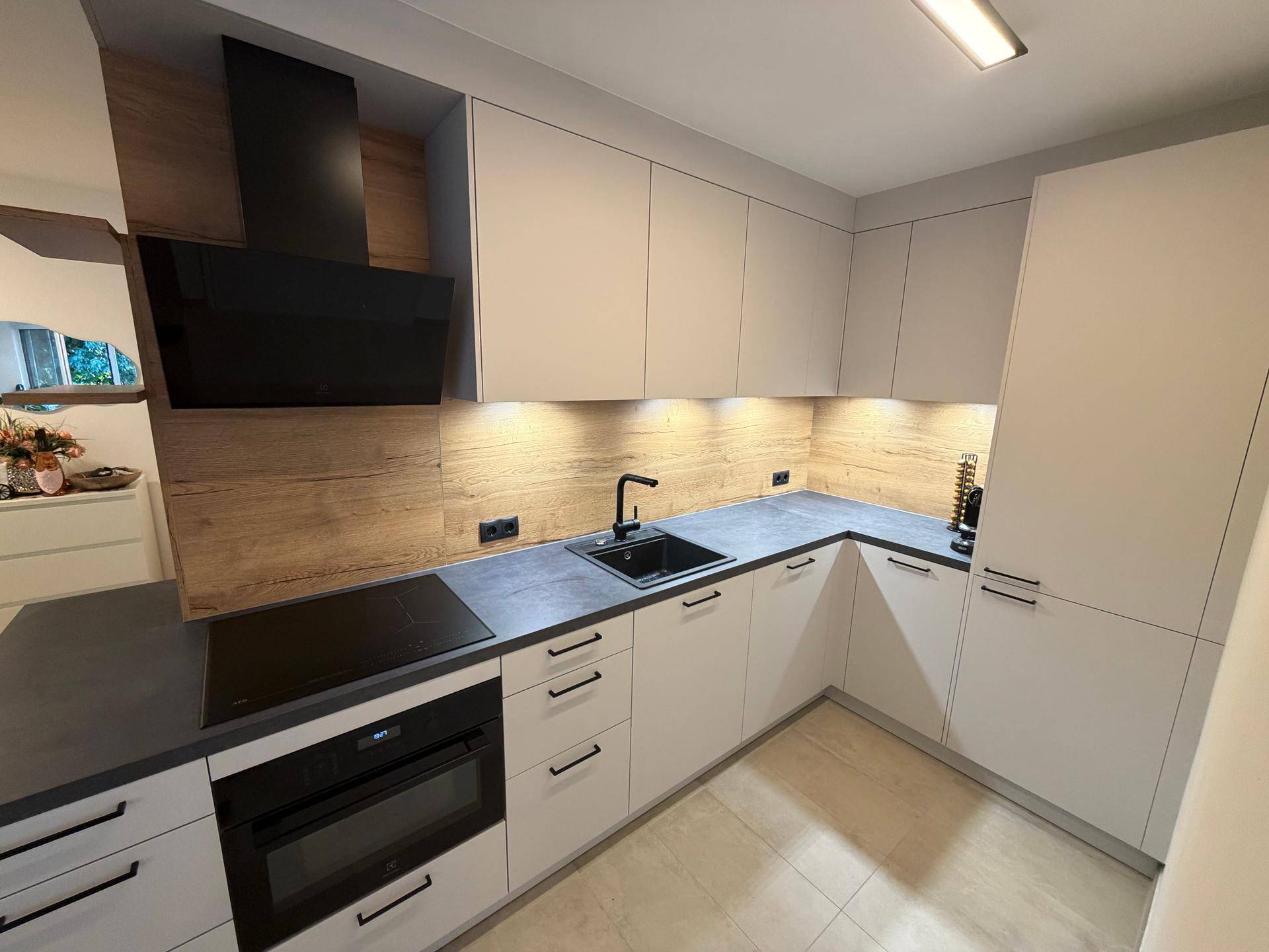 Detailansicht der modernen Küche mit integrierten Geräten, Spüle und Holzrückwand.