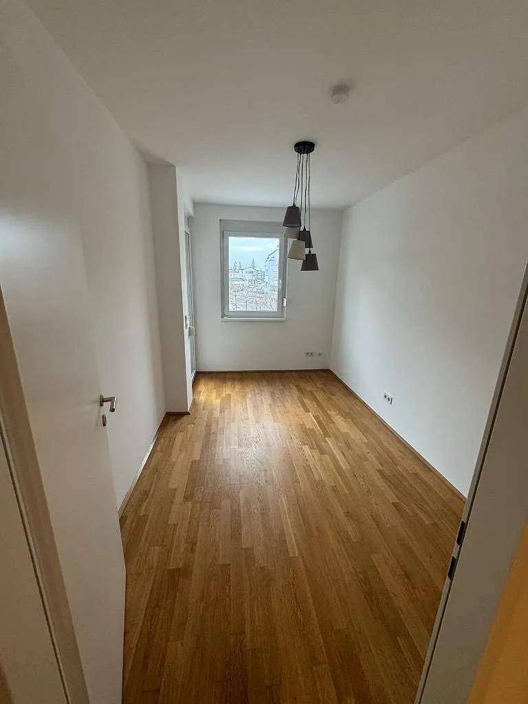 Ruhiges Zimmer mit Parkettboden und einem Fenster, das viel Tageslicht hereinlässt.