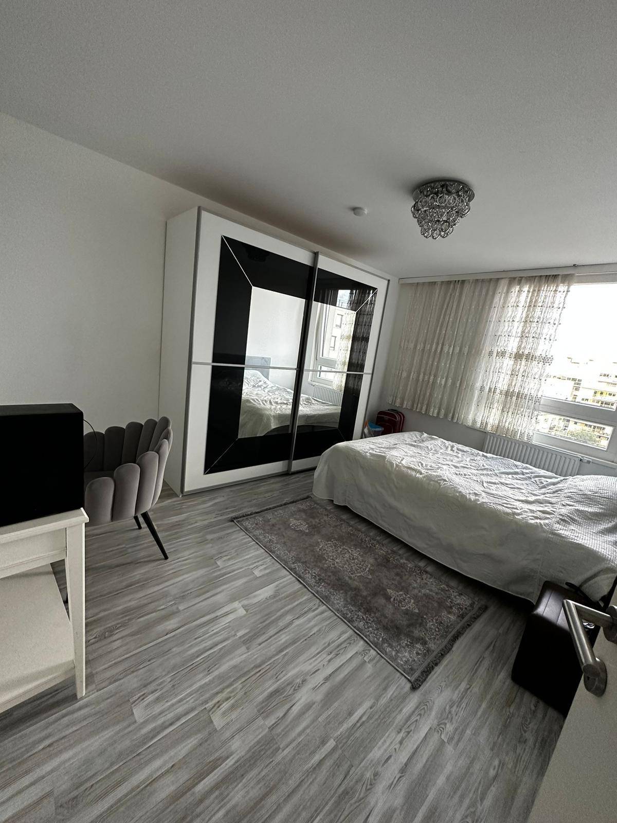 Helles Schlafzimmer mit großem Kleiderschrank, bequemen Bett und Blick nach draußen.