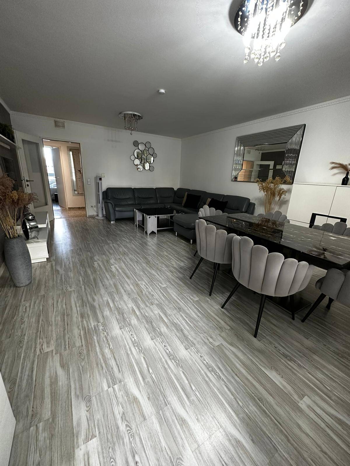 Geräumiger Wohn-Essbereich mit modernem Laminatboden, großem Sofa und elegantem Esstisch.