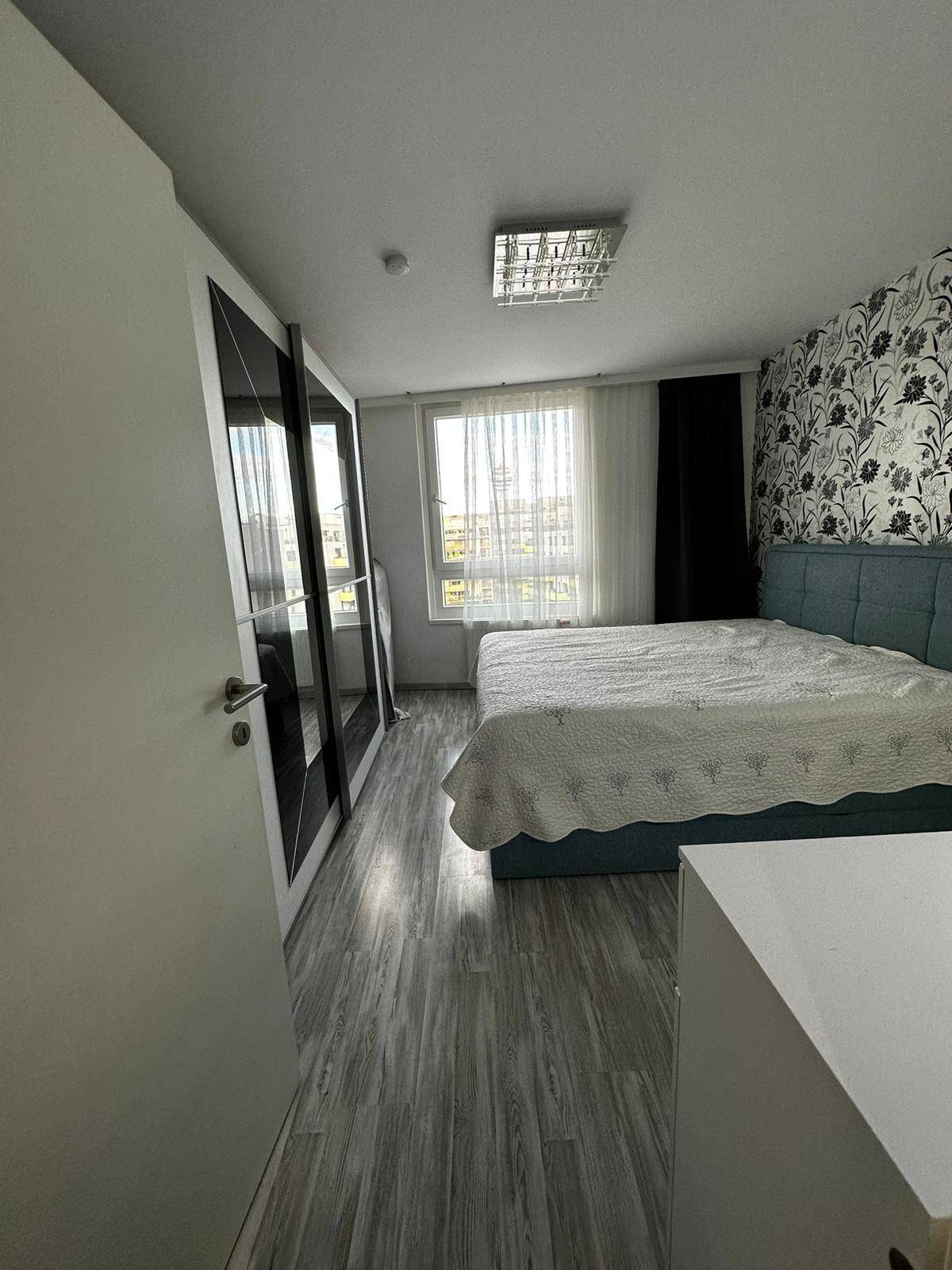 Gemütliches Schlafzimmer mit floraler Tapete, großem Bett und modernem Kleiderschrank.