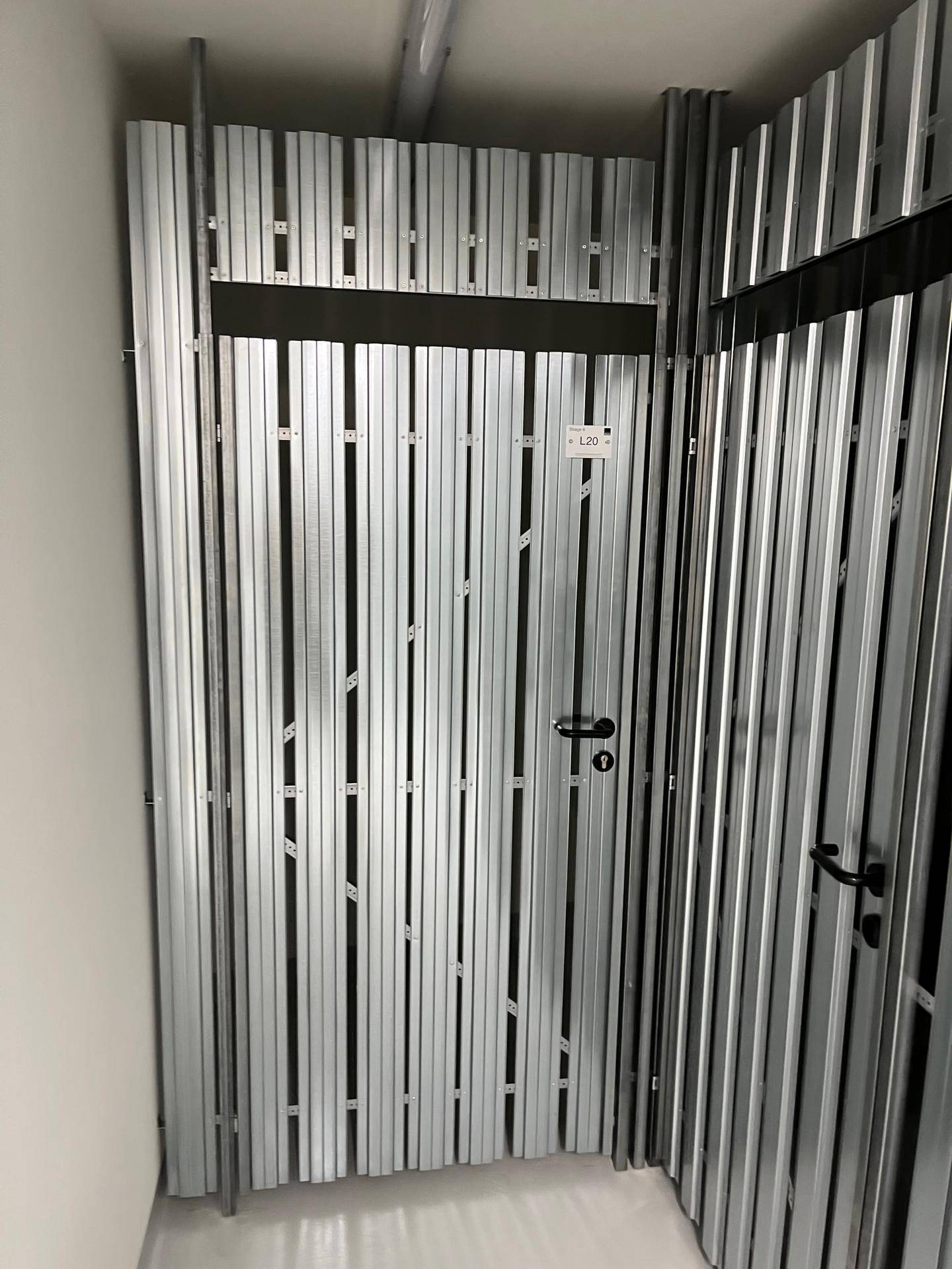 Eingang zu einem Lagerabteil mit Metalltür und Nummerierung im modernen Kellerbereich.