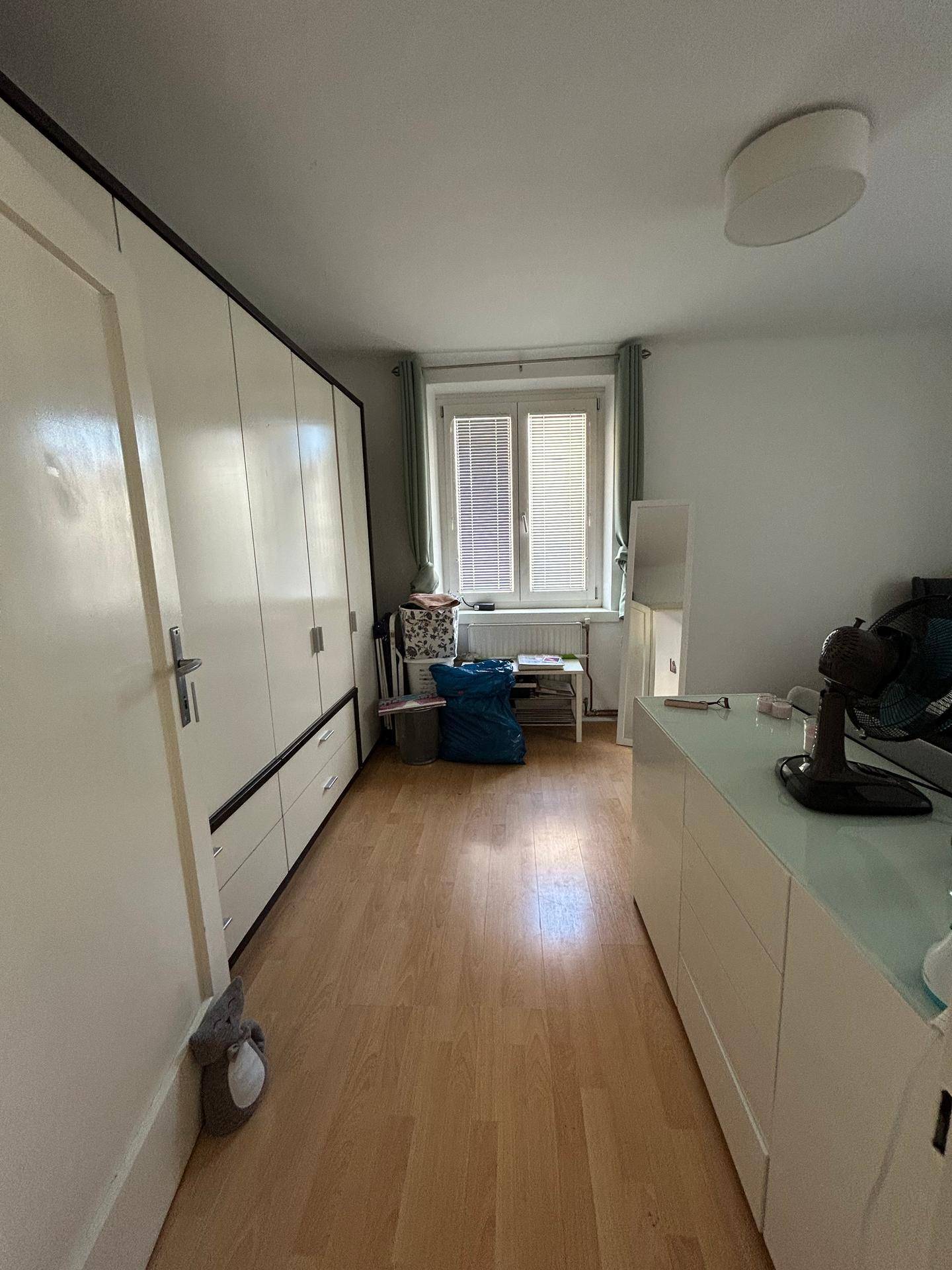 Helles Schlafzimmer mit großem Kleiderschrank, Schreibtisch und Fenster für natürliche Belichtung.