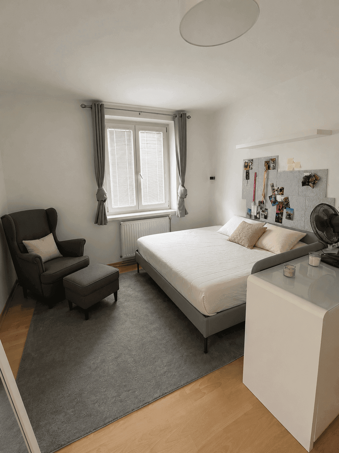 Gemütliches Schlafzimmer mit Doppelbett, Sessel und Fenster mit Jalousien für Privatsphäre.