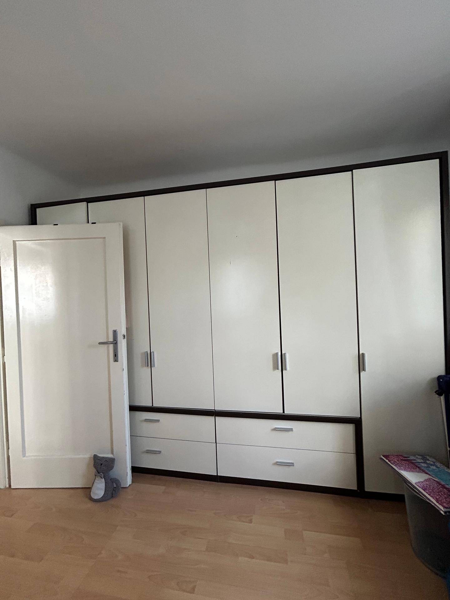 Großer weißer Kleiderschrank mit vielen Fächern und Schubladen bietet viel Stauraum im Schlafzimmer.