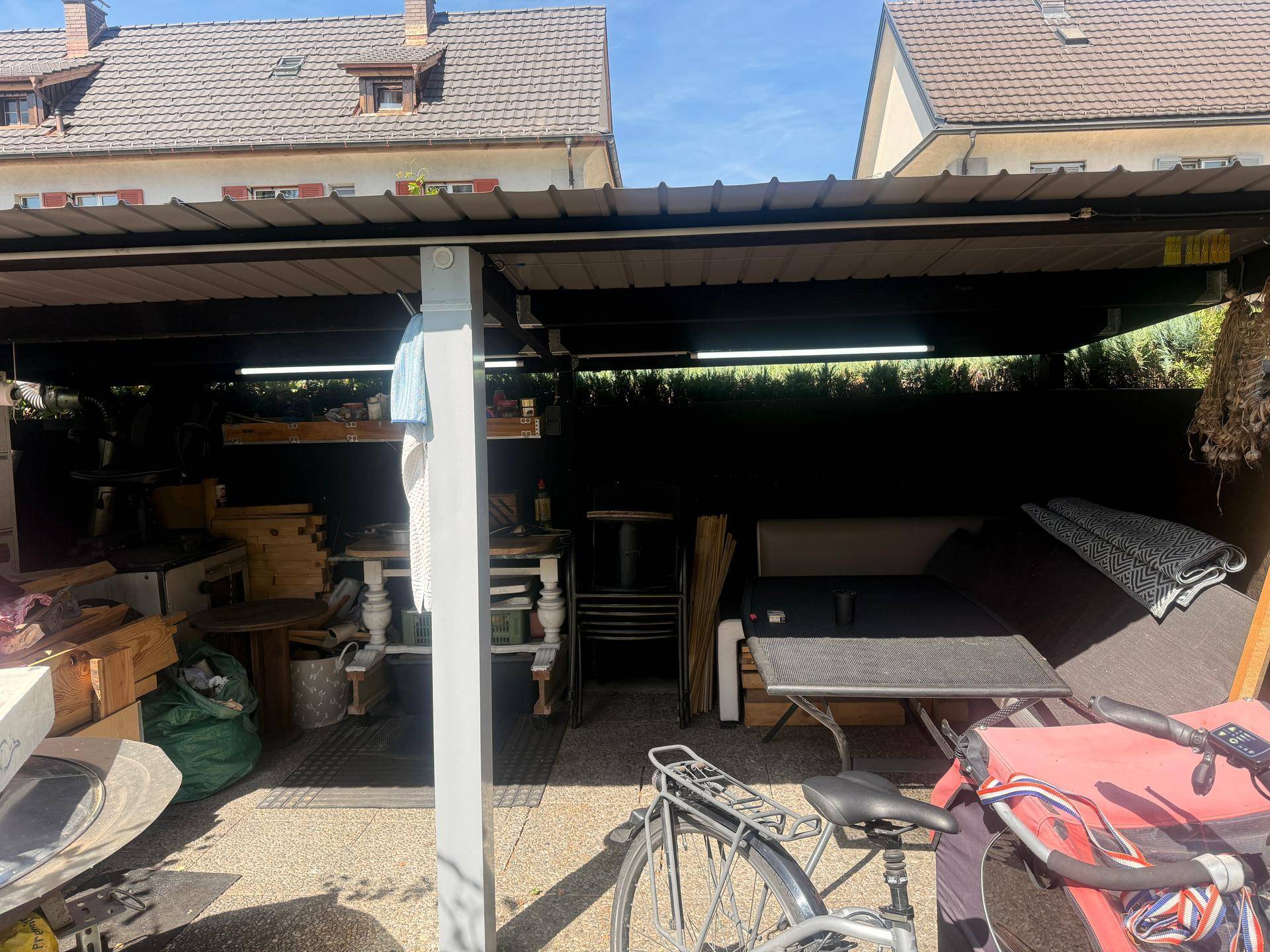Breitere Ansicht des überdachten Außenbereichs, der als vielseitiger Lager- und Arbeitsplatz genutzt wird.