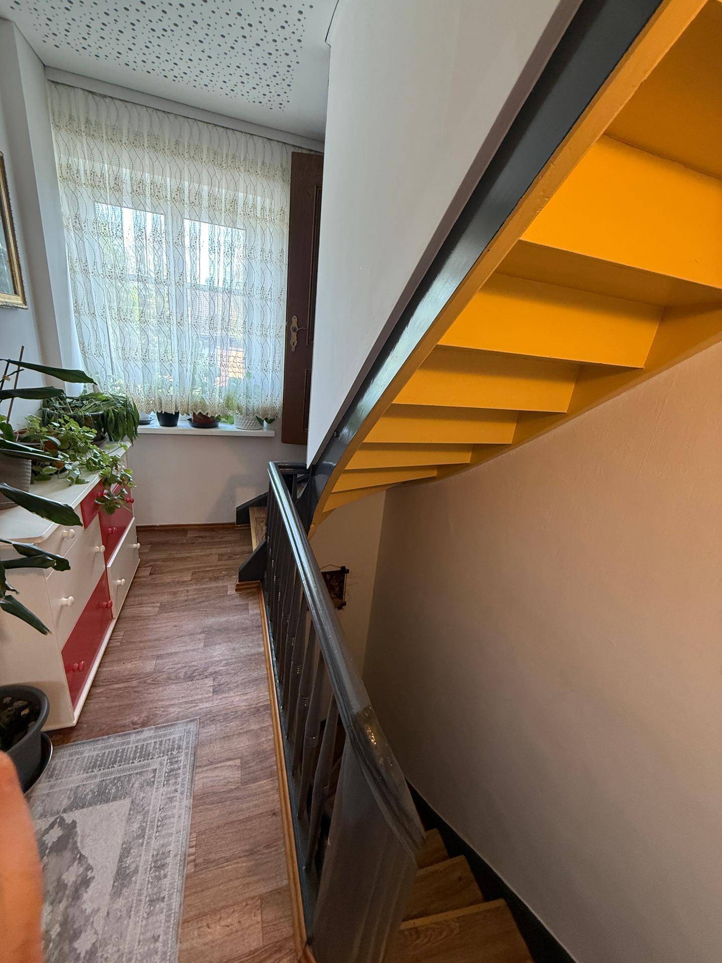 Treppenhaus mit gelb gestrichener Unterseite der Stufen und einem Fenster, das Tageslicht hereinlässt.