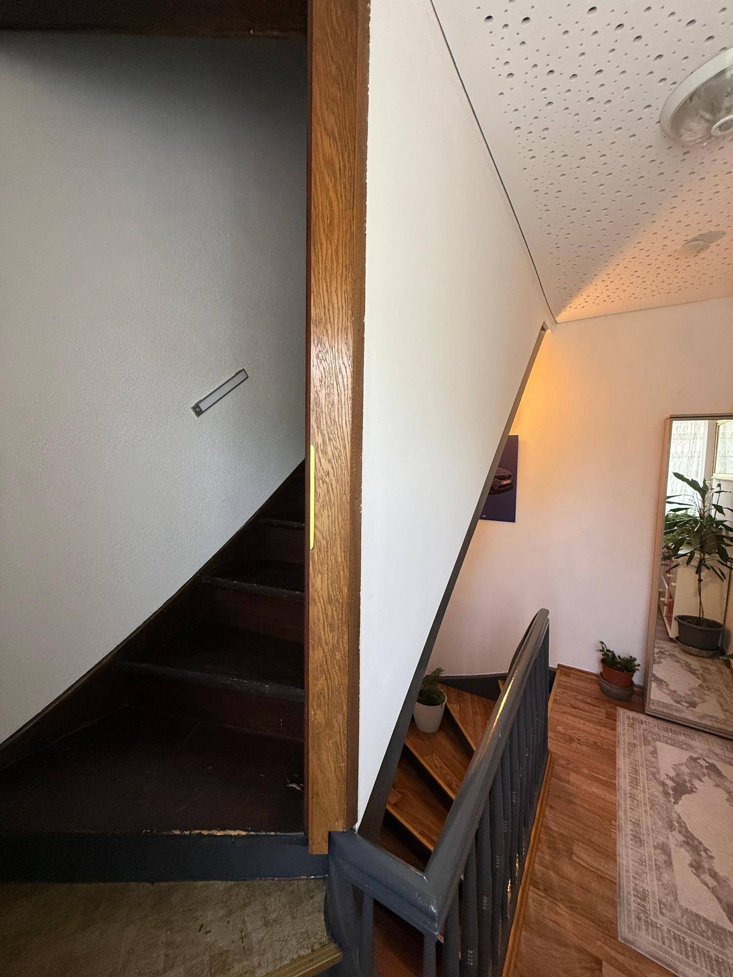 Treppenhaus mit Holzbalken und einem Spiegel, der den Raum optisch vergrößert.