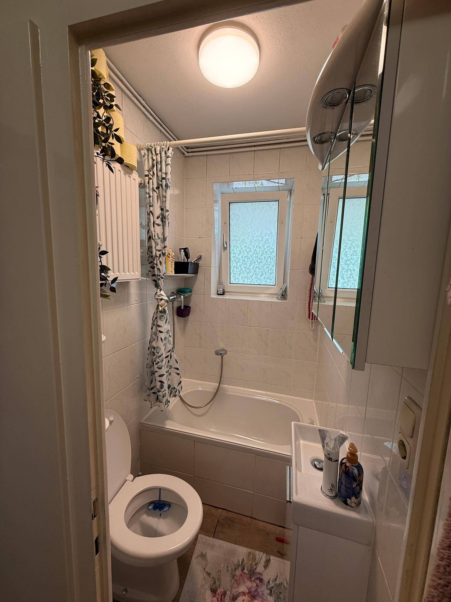 Kleines Badezimmer mit Badewanne, Toilette, Waschbecken und einem Fenster.