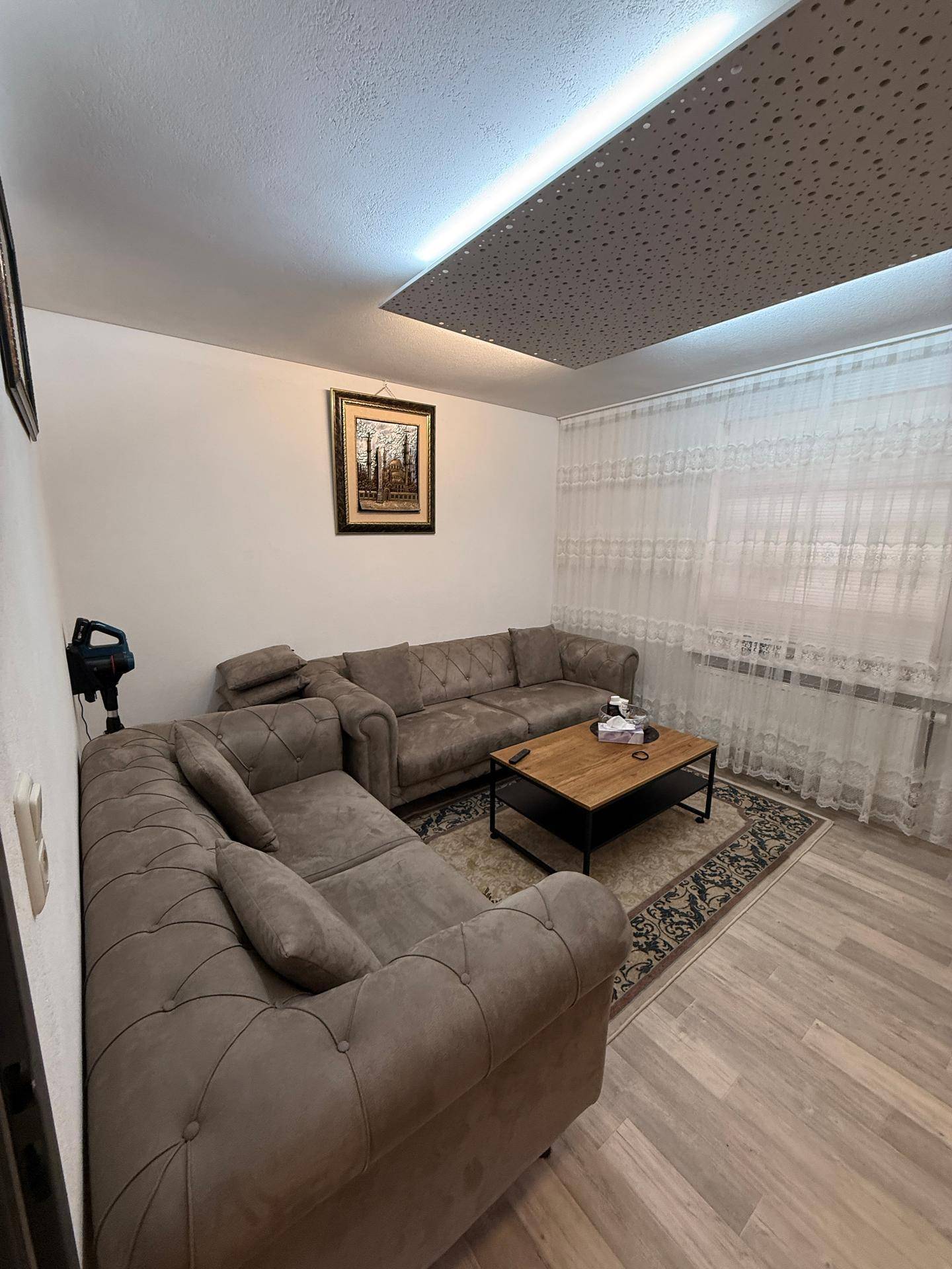 Wohnzimmer mit bequemer Eckcouch, Holztisch und einem Teppich auf hellem Laminatboden.