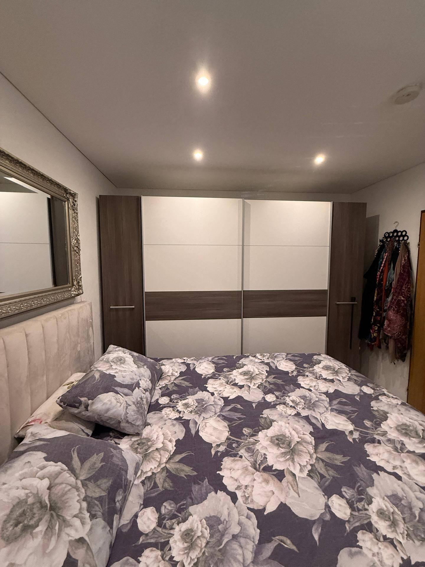 Schlafzimmer mit großem Bett, floraler Bettwäsche und einem modernen Kleiderschrank.