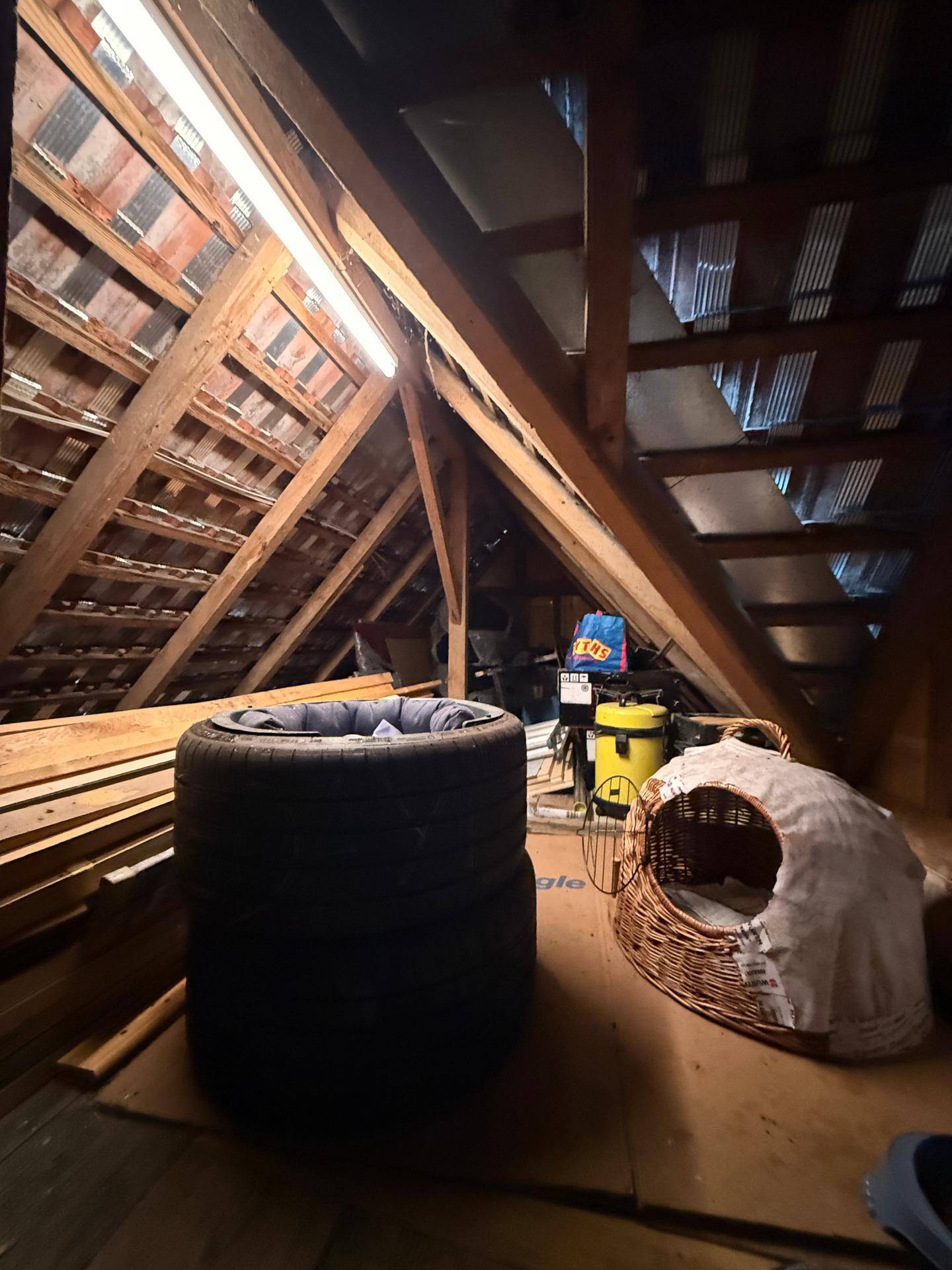 Unausgebauter Dachboden mit sichtbarer Holzkonstruktion, Lagerflächen und verschiedenen Gegenständen.