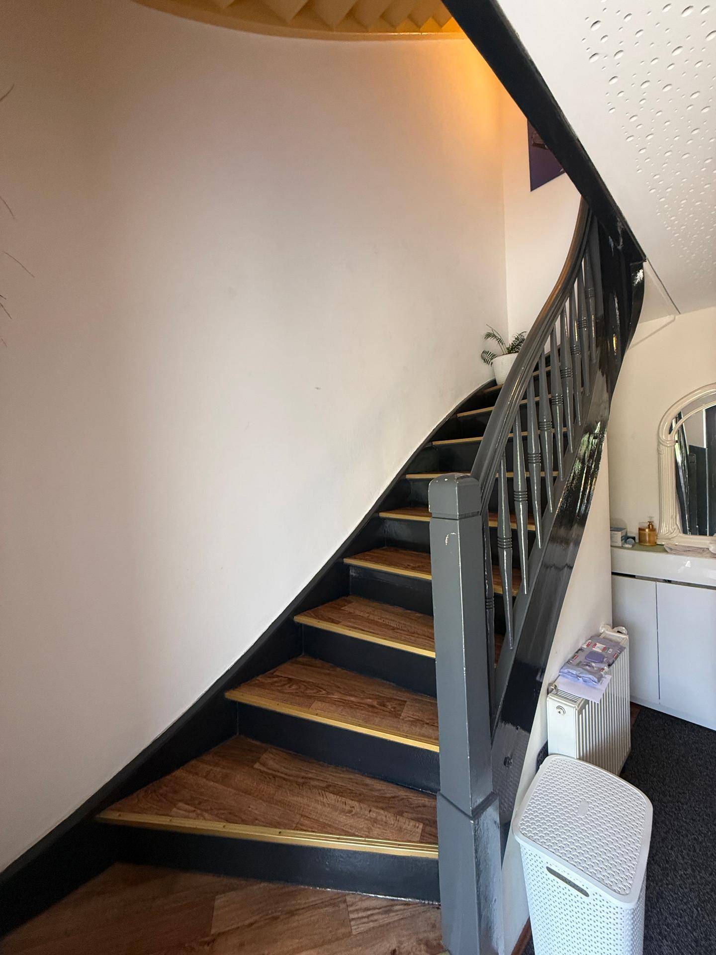 Treppenhaus mit dunklem Geländer und Holzstufen, das in die obere Etage führt.