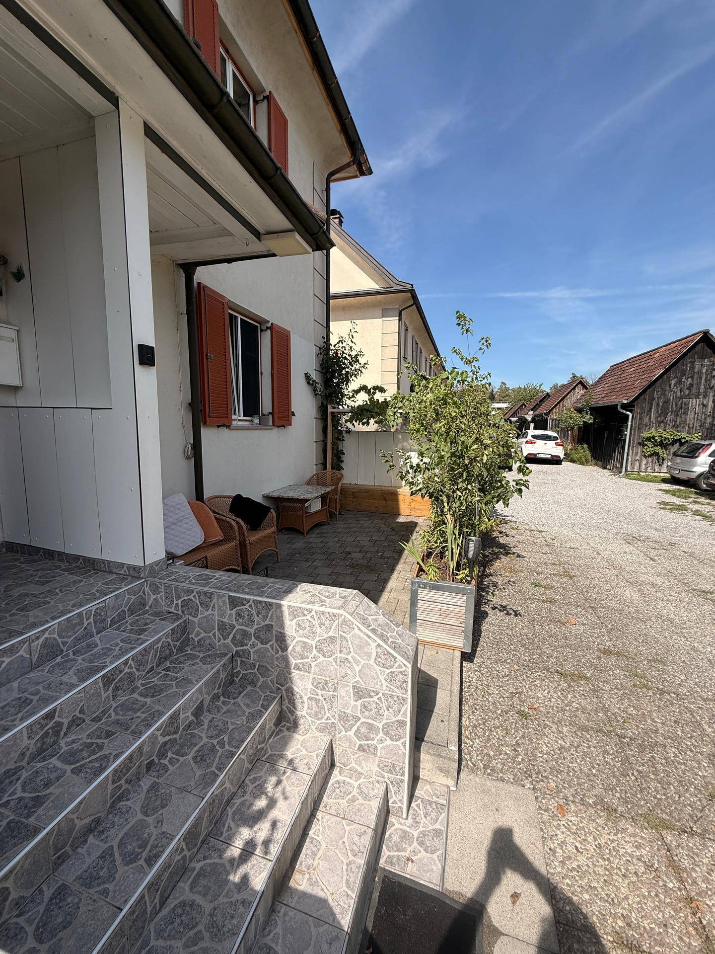 Eingangsbereich des Hauses mit gefliester Treppe und einem kleinen, möblierten Außenbereich daneben.