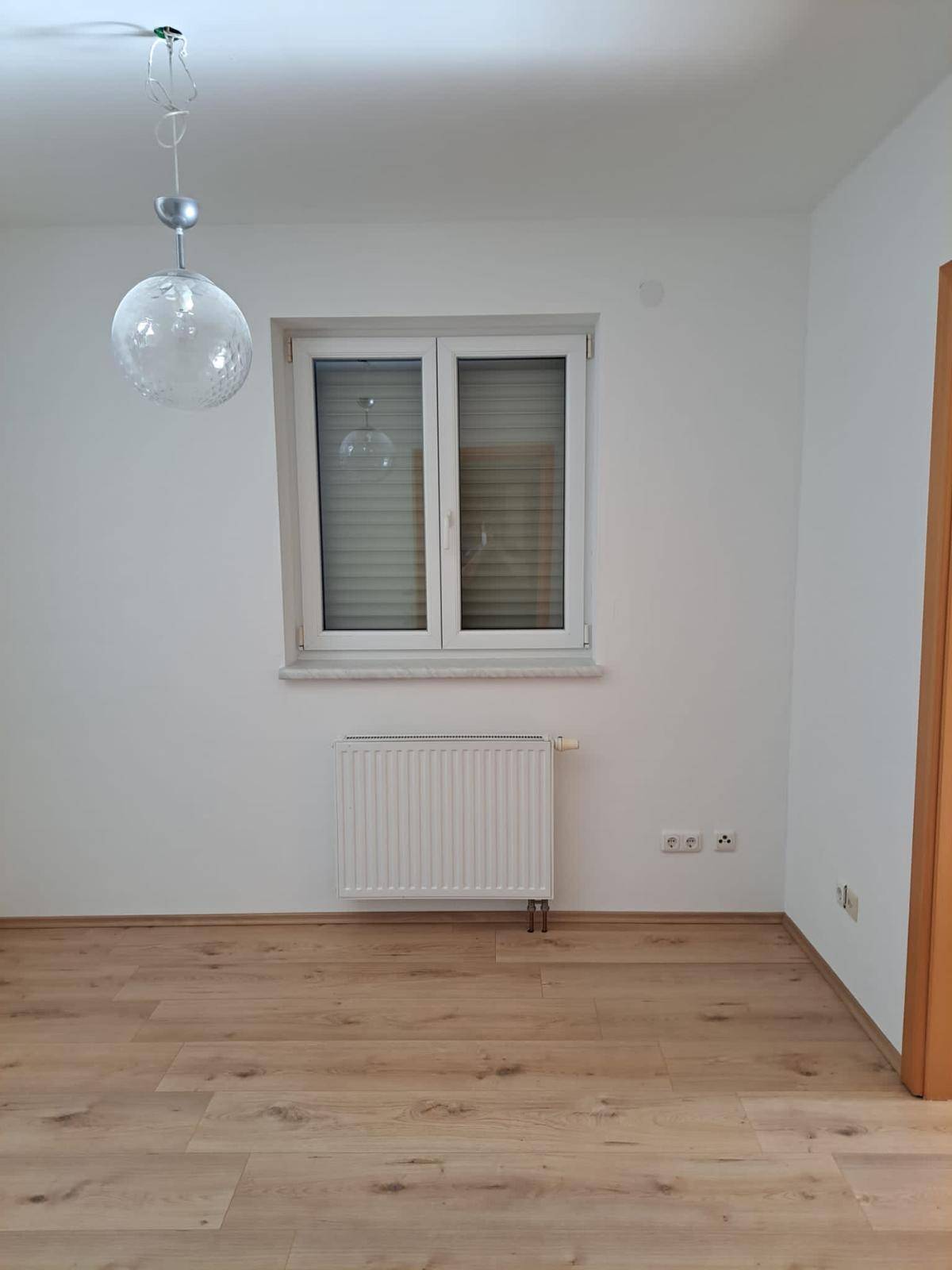 Freundliches Zimmer mit Laminatboden und großem Fenster, ideal für Kinder oder Gäste.