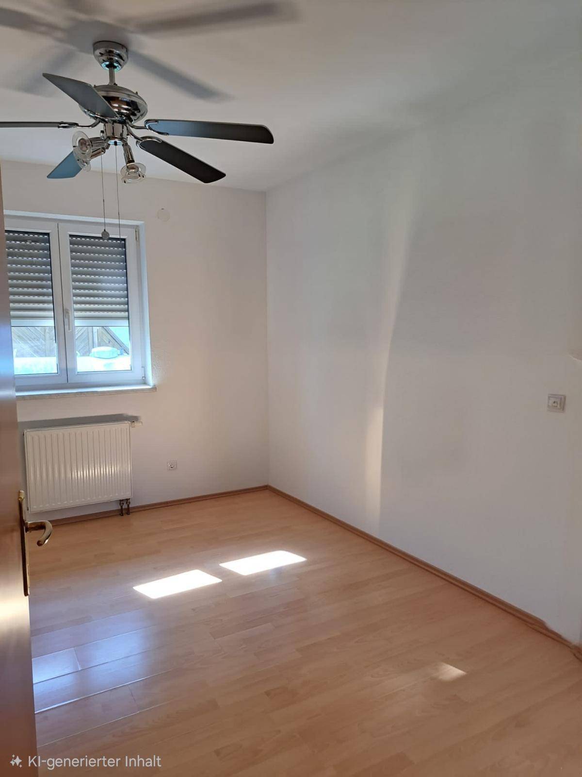 Helles Zimmer mit Laminatboden, Deckenventilator und Fenster mit Rollladen.