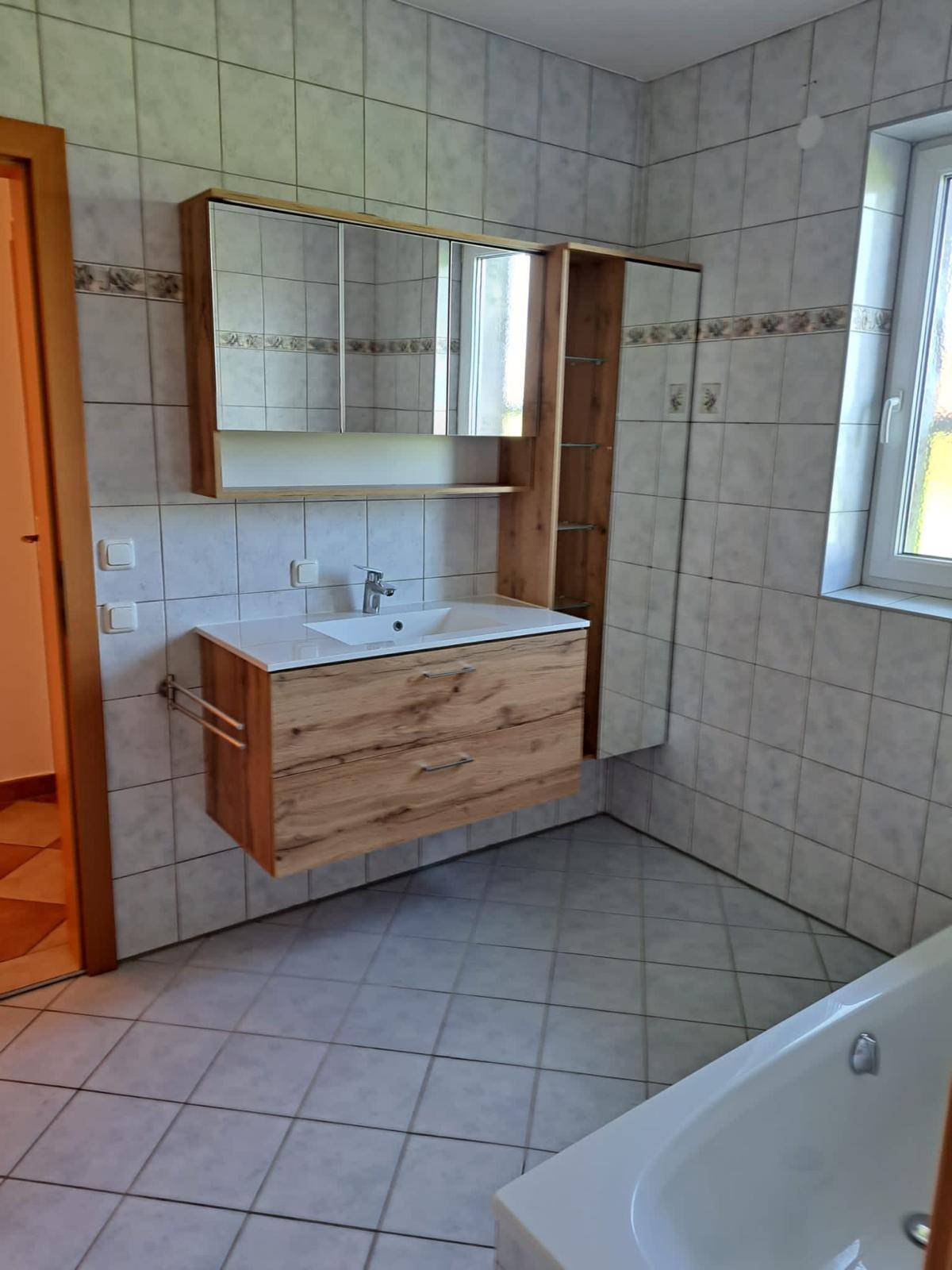 Modernes Badezimmer mit Waschtischunterschrank, Spiegelschrank und Fenster.