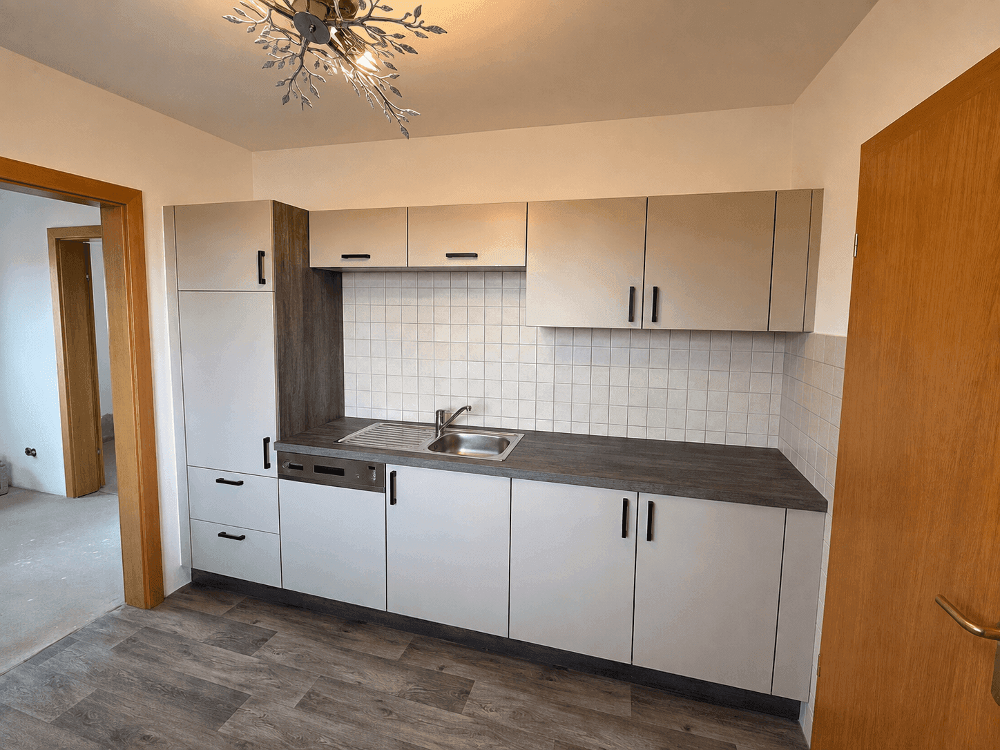 Neue Einbauküche in hellem Grau mit Spülbecken, Geschirrspüler und viel Stauraum.
