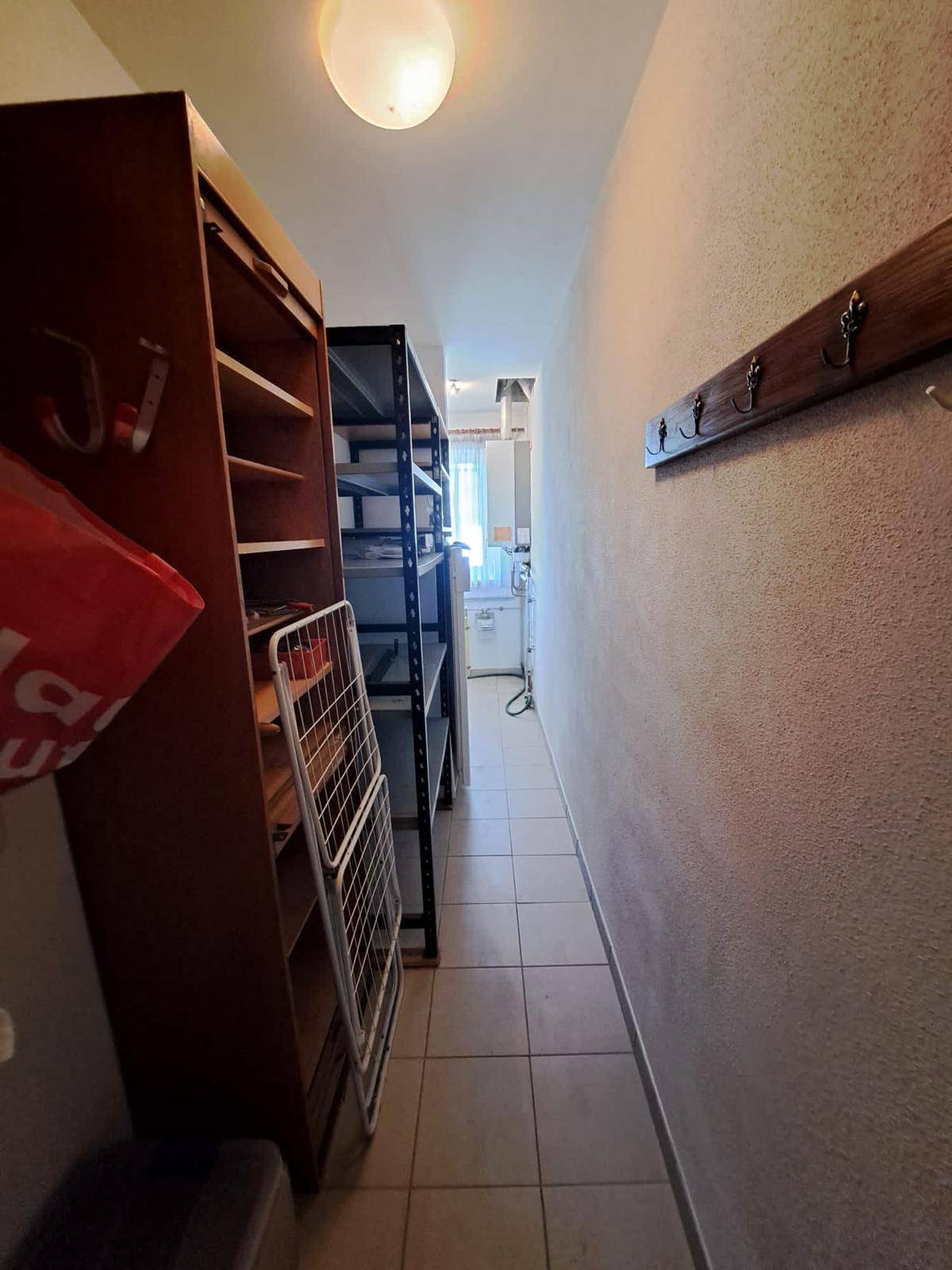 Praktischer Abstellraum mit Regalen und Fliesenboden, ideal für Vorräte und Haushaltsgeräte.