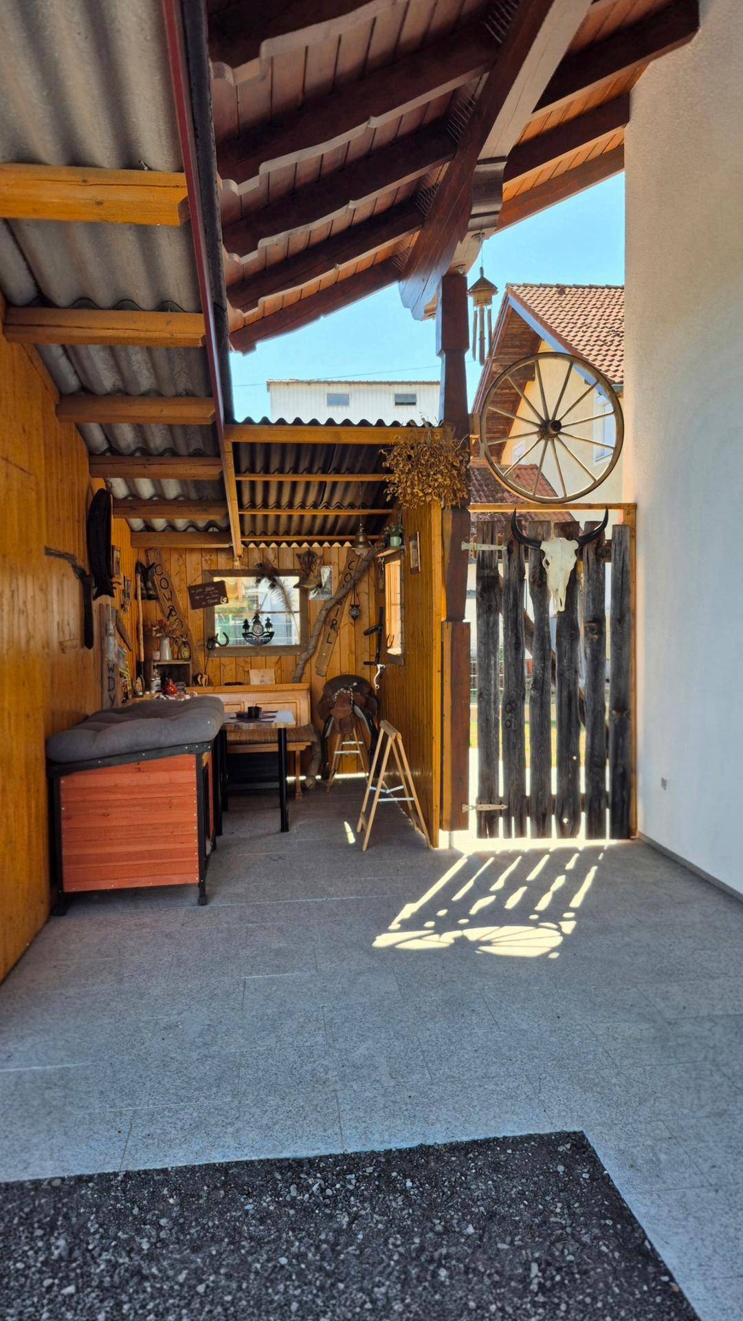 Gemütliche überdachte Loggia mit Holzelementen und rustikaler Dekoration, ideal zum Entspannen.