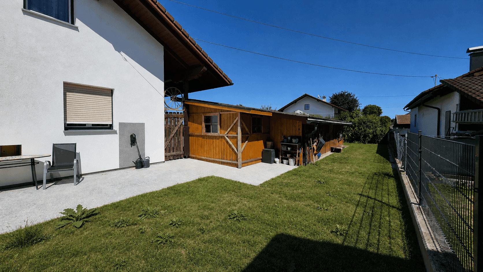 Weitläufiger Gartenbereich mit Rasen, Holzschuppen und Zaun, ideal für Freizeitaktivitäten.