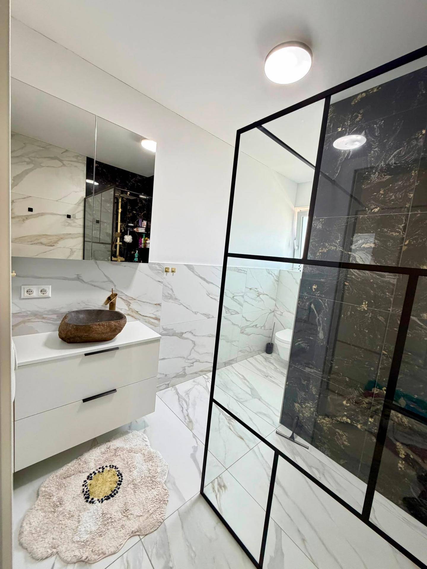 Elegantes Badezimmer mit begehbarer Dusche, Marmorfliesen und modernem Design.
