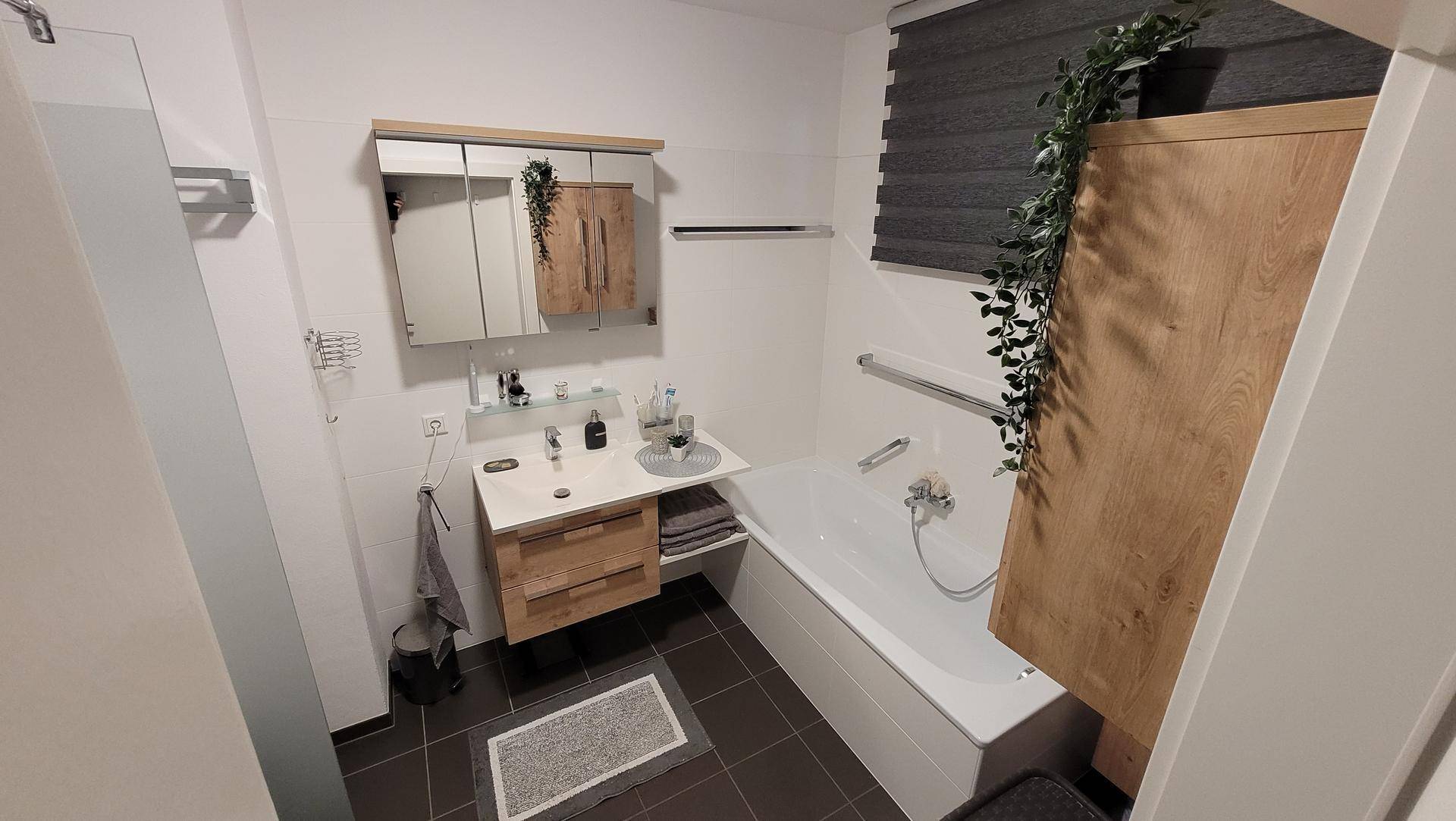 Helles Badezimmer mit Badewanne, Waschbecken und Spiegelschrank, modern und funktional.