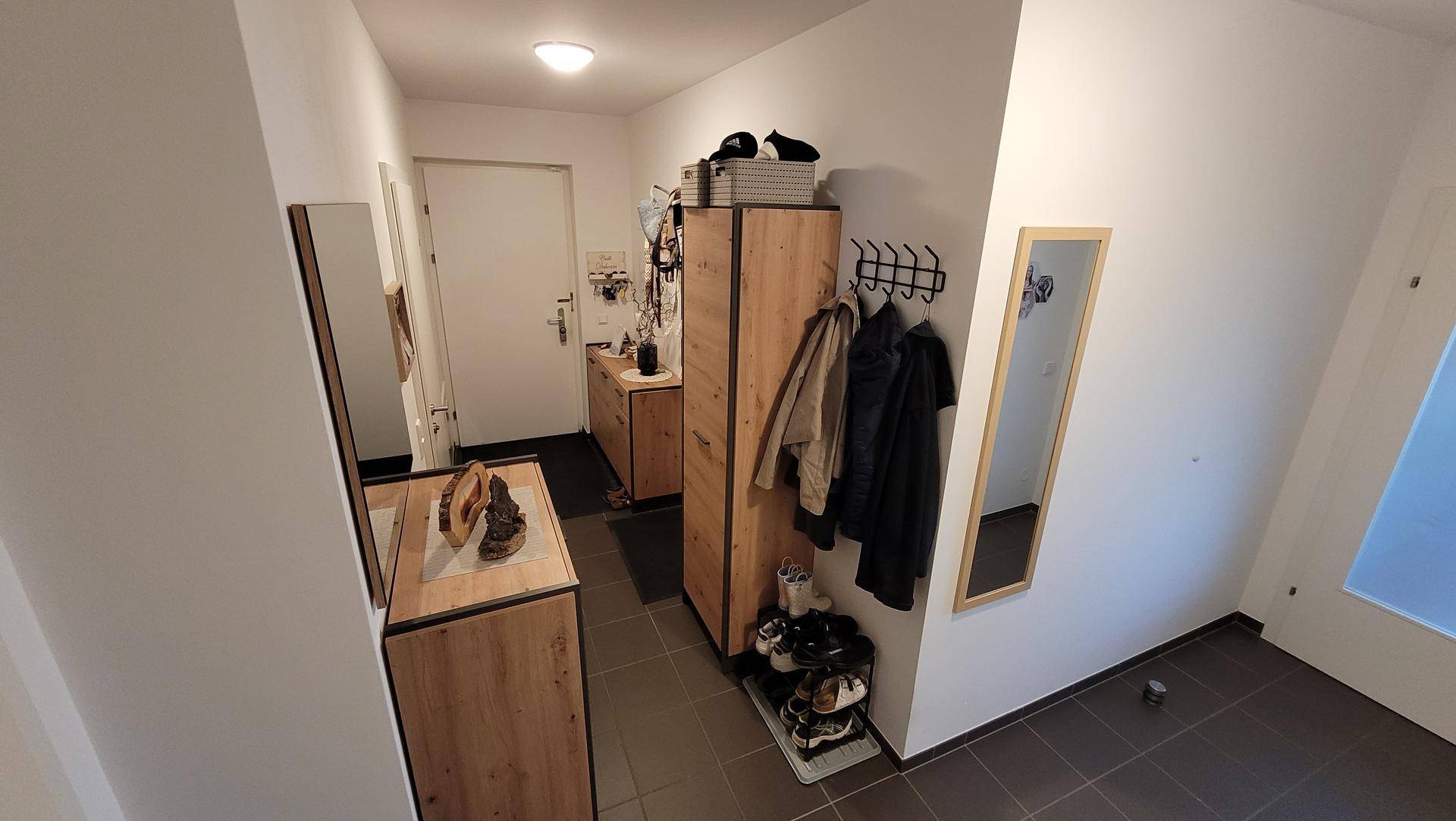 Heller Eingangsbereich mit Fliesenboden, Garderobe und Spiegeln, einladend gestaltet.